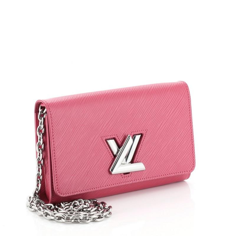 This Louis Vuitton Twist Chain Wallet Epi Leather, crafted from pink epi leather, features a shoulder chain strap and silver-tone hardware. Its flap with twist lock closure opens to a pink leather interior with zip pocket and multiple card slots.