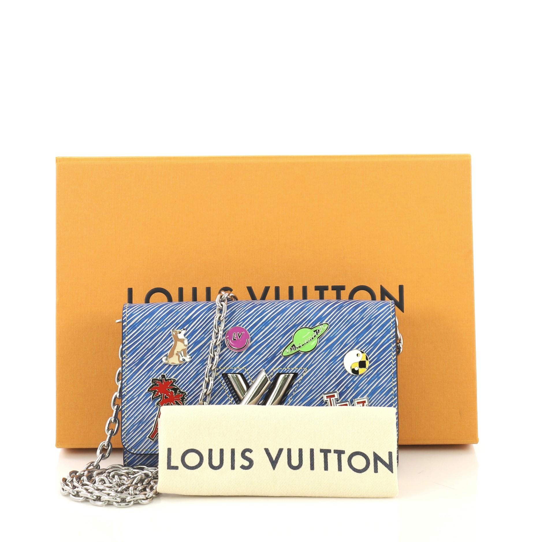 This Louis Vuitton Twist Chain Wallet Limited Edition Pin Embellished Epi Leather, crafted from blue epi leather, features a shoulder chain strap, pin embellishments, and silver-tone hardware. Its flap with twist lock closure opens to a gray leather