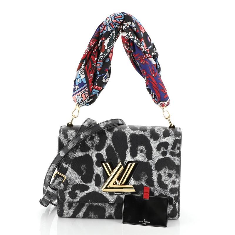 This Louis Vuitton Twist Convertible Handbag Wild Animal Print Canvas MM, crafted from black canvas, features detachable strap, wild animal print, frontal flap, and gold-tone hardware. Its LV twist lock closure opens to a red microfiber interior