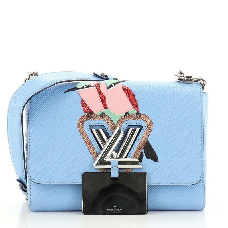 This Louis Vuitton Twist Handbag Bird Motif Epi Leather MM, crafted from blue epi leather, features chain link strap with leather pad, frontal flap with bird motif pattern, and silver-tone hardware. Its LV twist lock closure opens to a blue