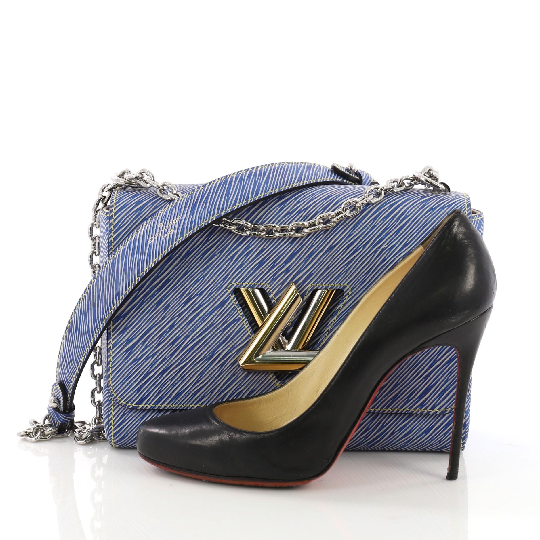 This Louis Vuitton Twist Handbag Epi Leather MM, crafted from blue epi leather, features a chain link strap with leather pad, frontal flap, and silver and gold-tone hardware. Its LV twist lock closure opens to a light grey microfiber interior with