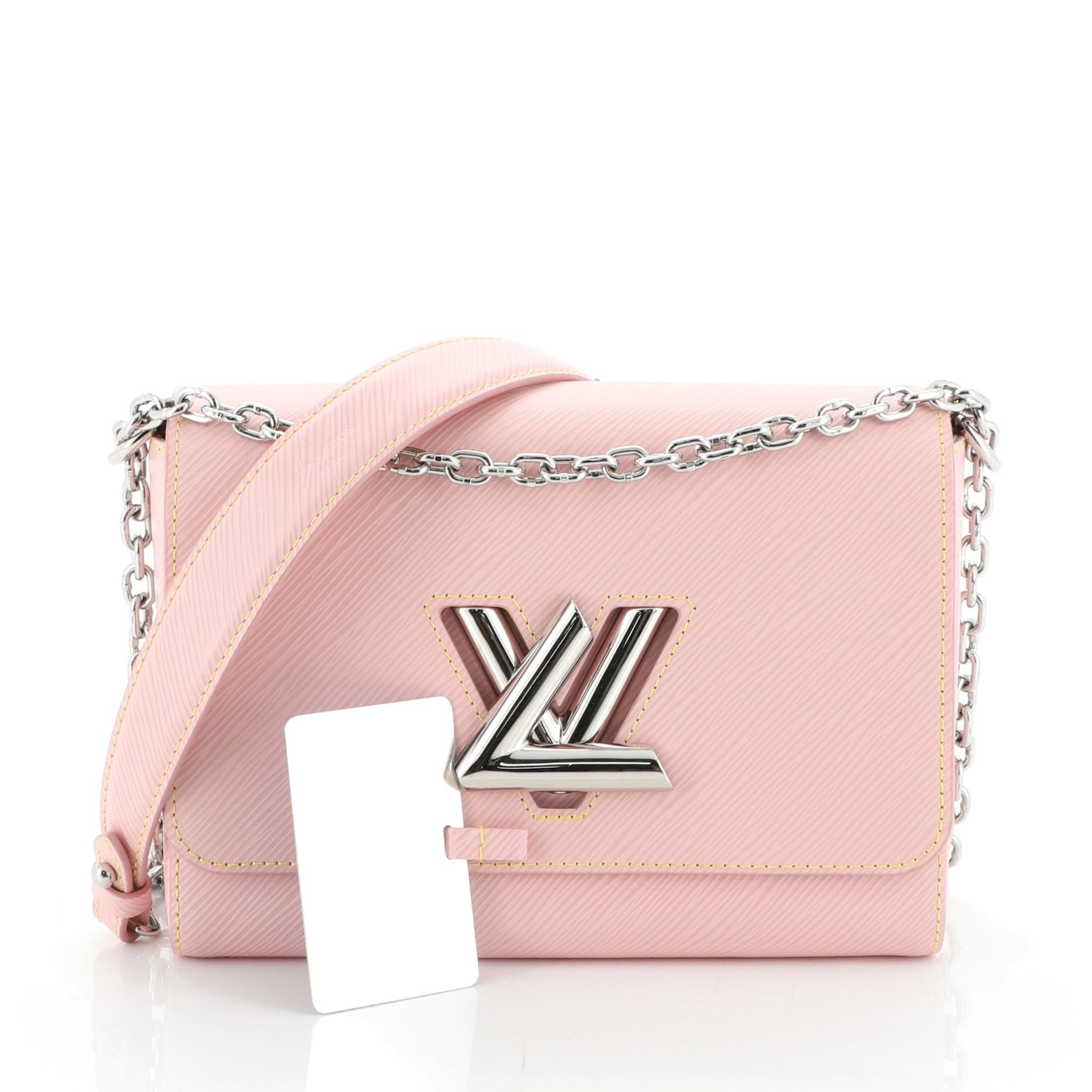 This Louis Vuitton Twist Handbag Epi Leather MM, crafted from pink epi leather, features chain link strap with leather pad, frontal flap, and silver-tone hardware. Its LV twist lock closure opens to a neutral microfiber interior with slip pockets.