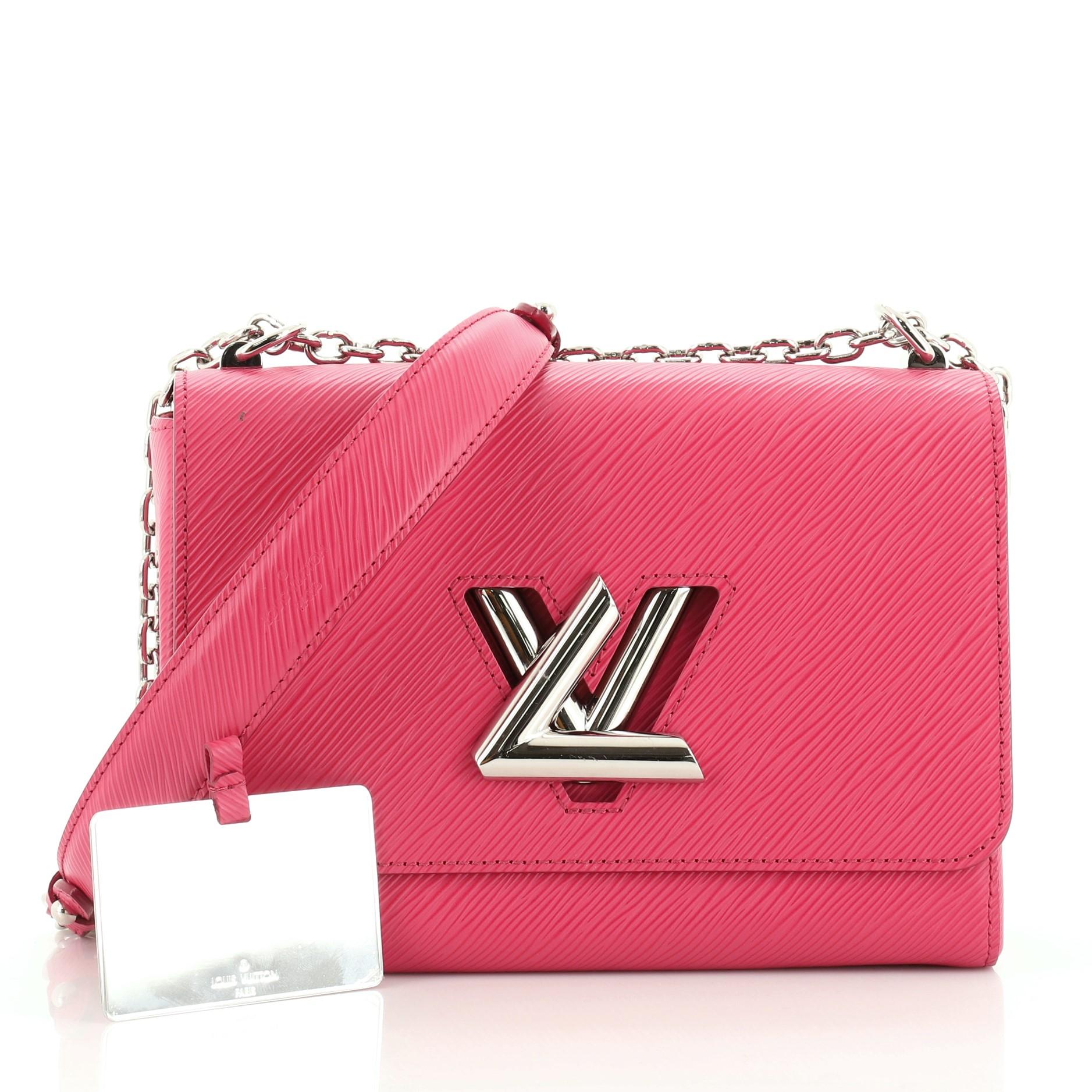This Louis Vuitton Twist Handbag Epi Leather MM, crafted from pink epi leather, features chain link strap with leather pad, frontal flap, and silver-tone hardware. Its LV twist lock closure opens to a pink microfiber interior with slip pockets.