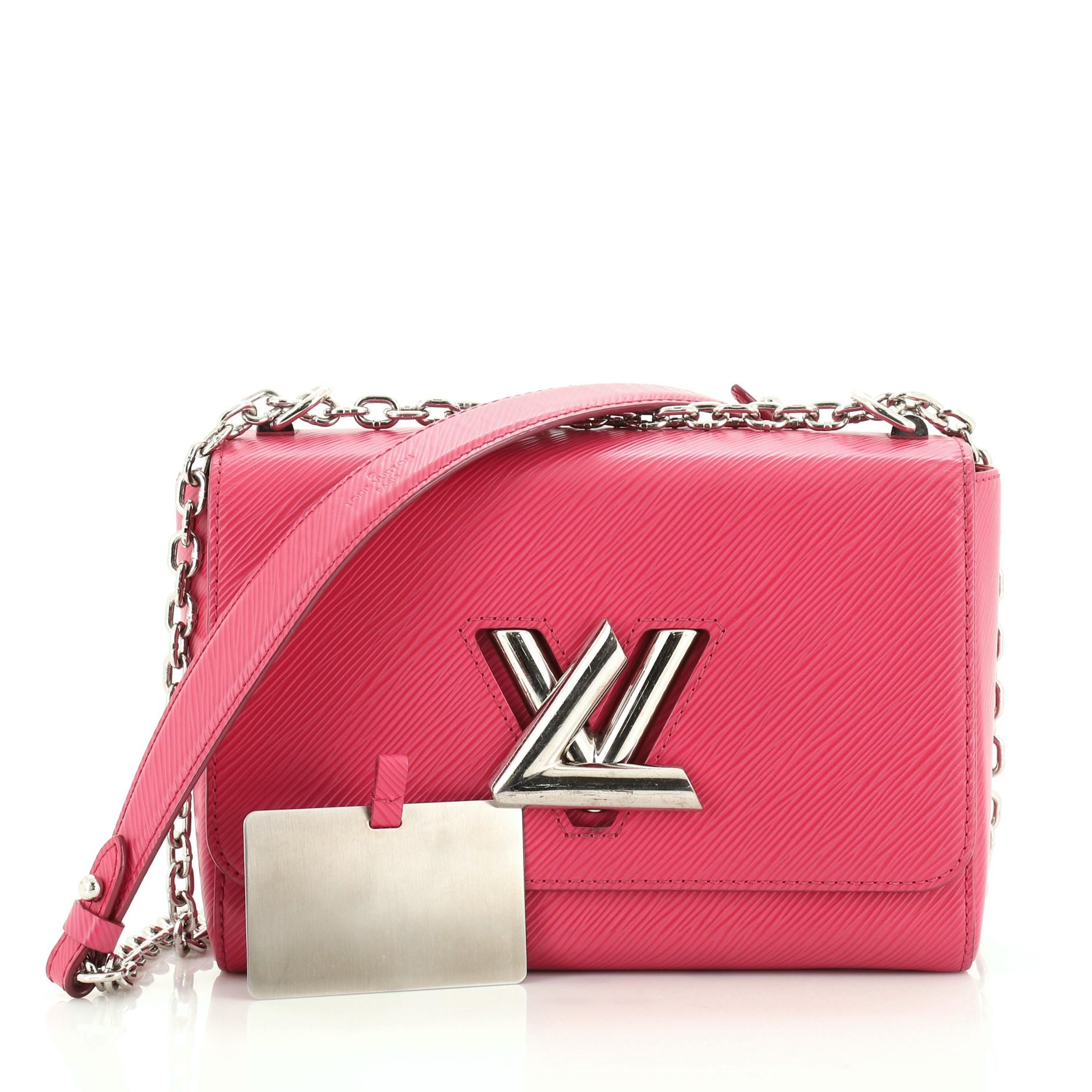 This Louis Vuitton Twist Handbag Epi Leather MM, crafted from pink epi leather, features chain link strap with leather pad, frontal flap, and silver-tone hardware. Its LV twist lock closure opens to a pink microfiber and leather interior with slip