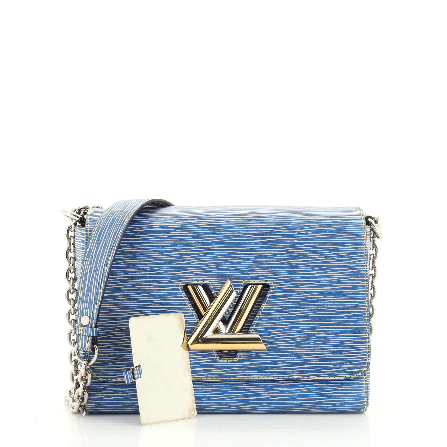 This Louis Vuitton Twist Handbag Epi Leather MM, crafted from blue epi leather, features chain link strap with leather pad, frontal flap, and gold and silver-tone hardware. Its LV twist lock closure opens to a neutral microfiber interior with slip