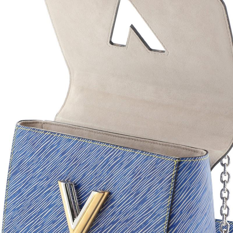 This Louis Vuitton Twist Handbag Epi Leather MM, crafted from blue epi leather, features chain link strap with leather pad, frontal flap, and silver-tone hardware. Its LV twist lock closure opens to a gray microfiber interior with slip pockets.