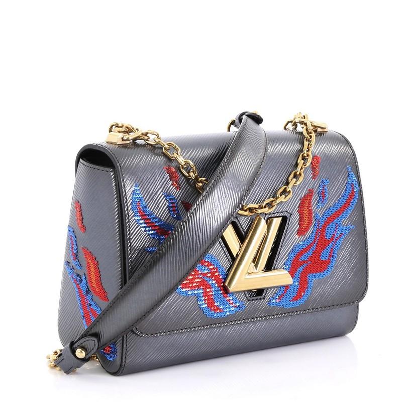 This Louis Vuitton Twist Handbag Epi Leather with Sequins MM, crafted in gray epi leather with sequins, features chain-link shoulder strap with leather pad and gold-tone hardware. Its twist-lock closure opens to a black microfiber interior with slip