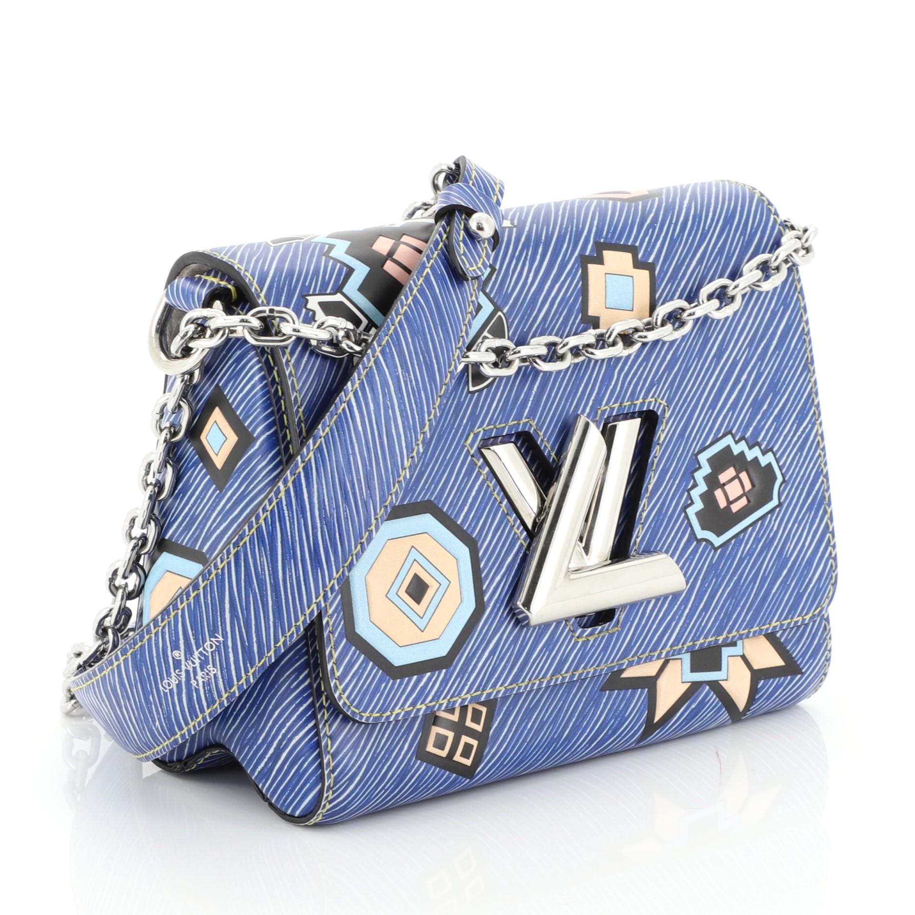 
This Louis Vuitton Twist Handbag Limited Edition Azteque Epi Leather MM, crafted from blue azteque epi leather, features long chain strap with leather pad and silver-tone hardware. Its flap with twist-lock closure opens to a neutral microfiber
