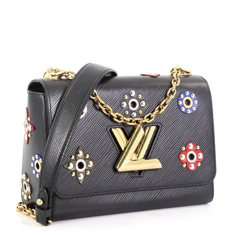 This Louis Vuitton Twist Handbag Limited Edition Mechanical Flowers Epi Leather MM, crafted from black epi leather, features chain link strap with leather pad, multicolor flowers with circular studs, and gold and silver-tone hardware. Its LV