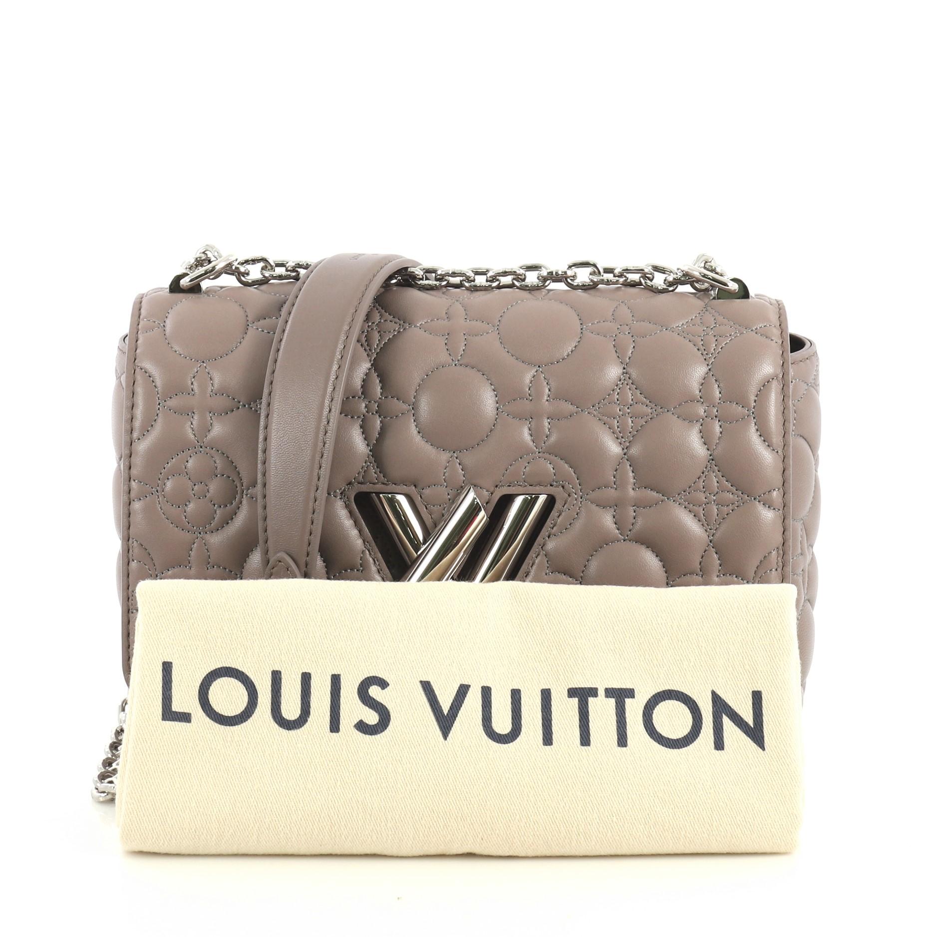 This Louis Vuitton Twist Handbag Malletage Flower Lambskin MM, crafted from purple malletage flower lambskin leather, features chain link strap with leather pad, frontal flap, and silver-tone hardware. Its LV twist lock closure opens to a purple