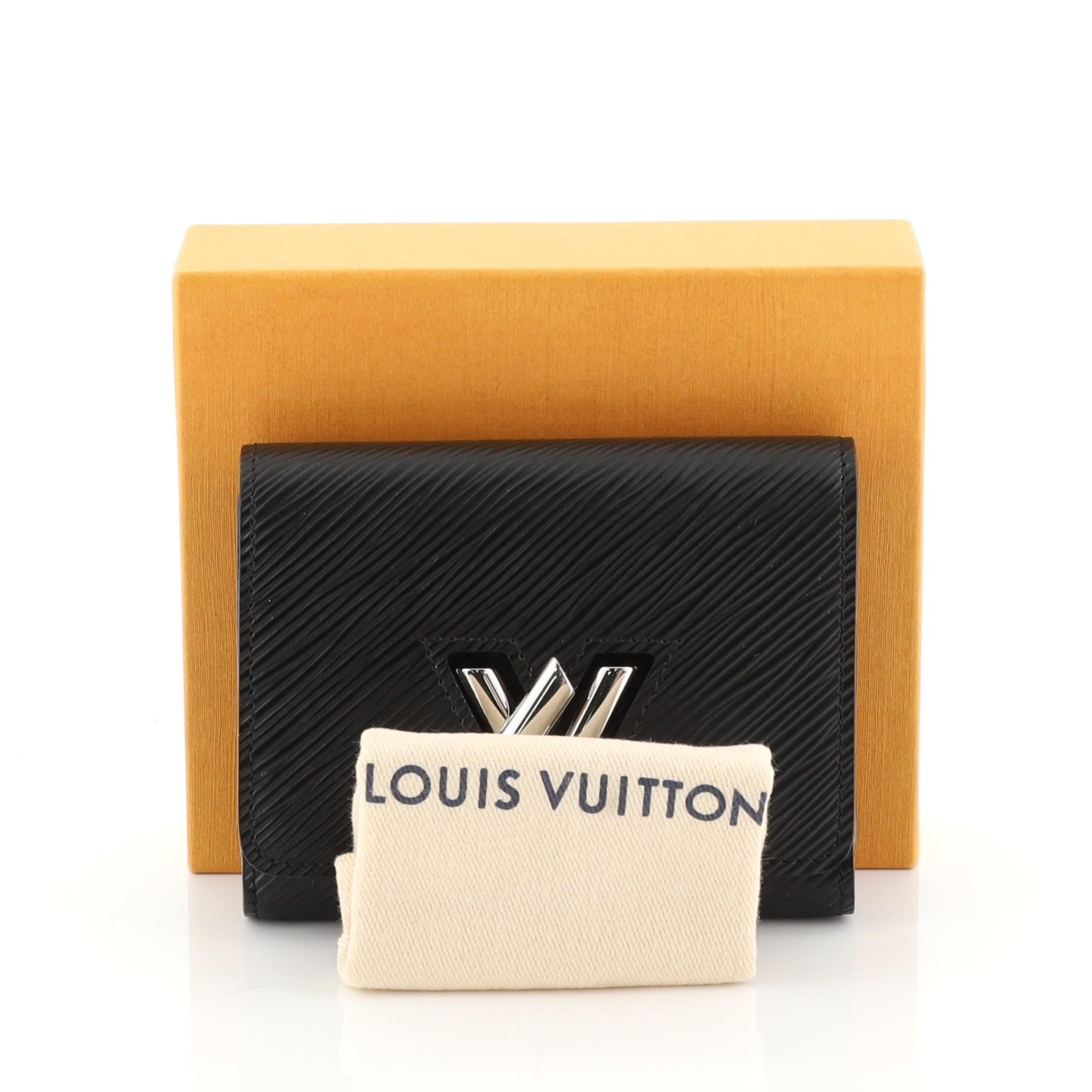 This Louis Vuitton Twist Wallet Epi Leather Compact, crafted from black epi leather, features silver-tone hardware. Its flap with LV twist lock closure opens to a black leather interior with multiple card slots and zip and slip pockets. Authenticity