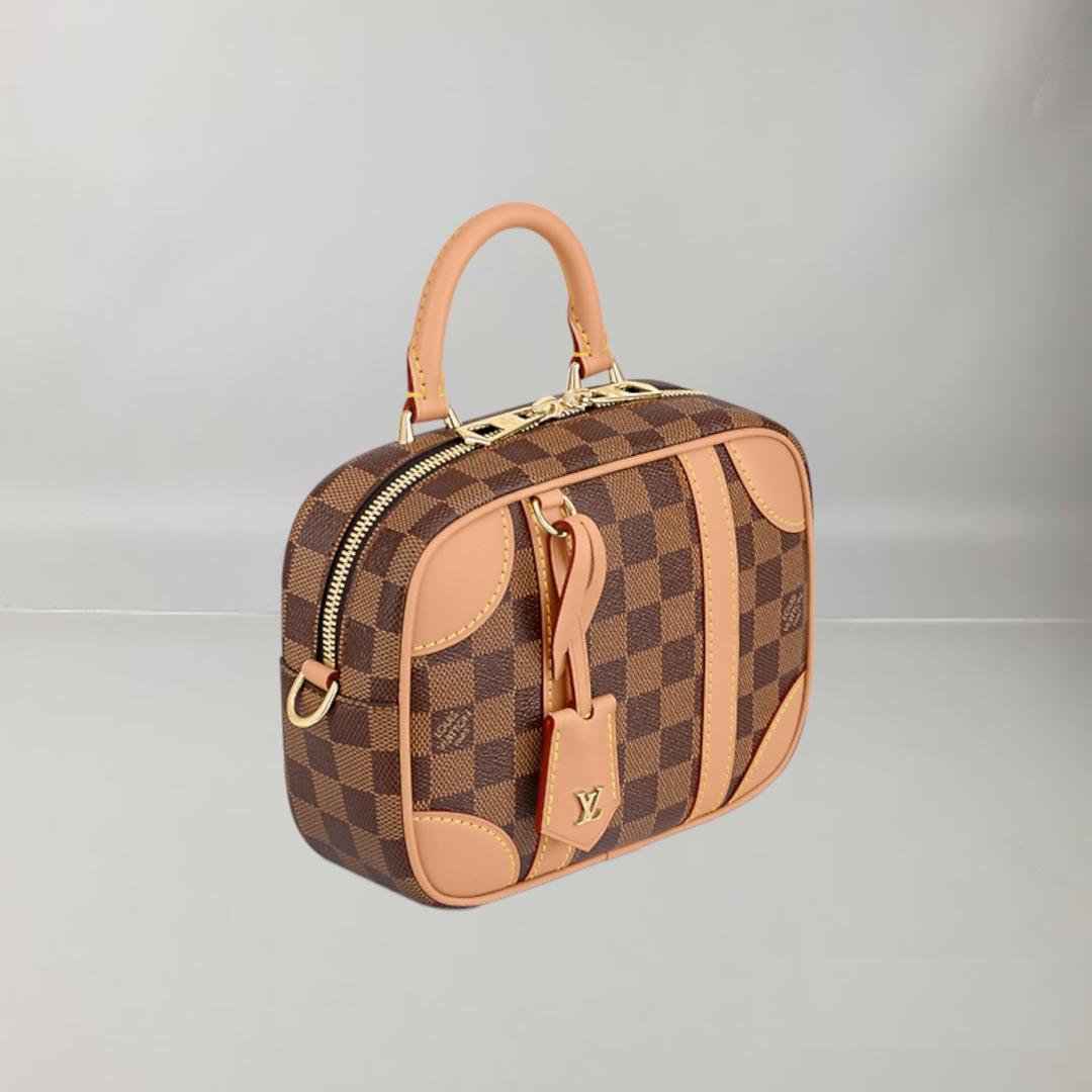 The compact Valisette Souple BB bag is inspired by vintage Louis Vuitton luggage. Made from Damier Ebene canvas, it features leather corners and bands on the side as well as an LV key bell. The inside is lined in Bordeaux-red textile and includes a