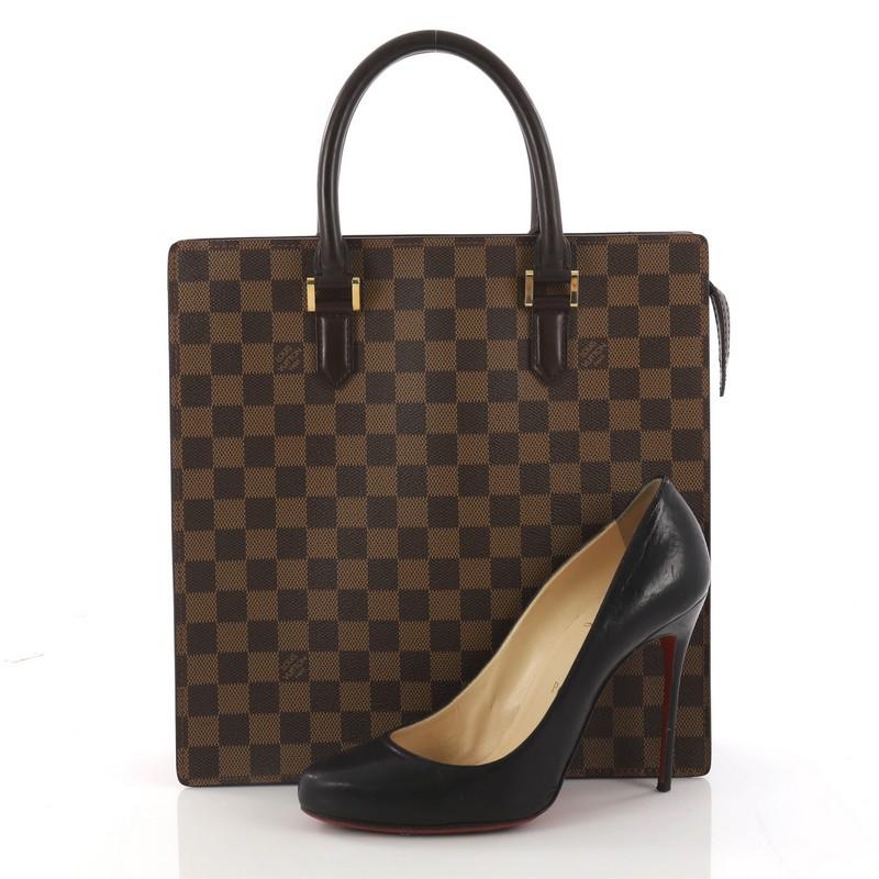 This authentic Louis Vuitton Venice Sac Plat Handbag Damier PM is a structured design perfect for everyday use. Crafted in iconic damier ebene coated canvas, this bag features simple shopper silhouette and dual-rolled leather handles. Its top zipper