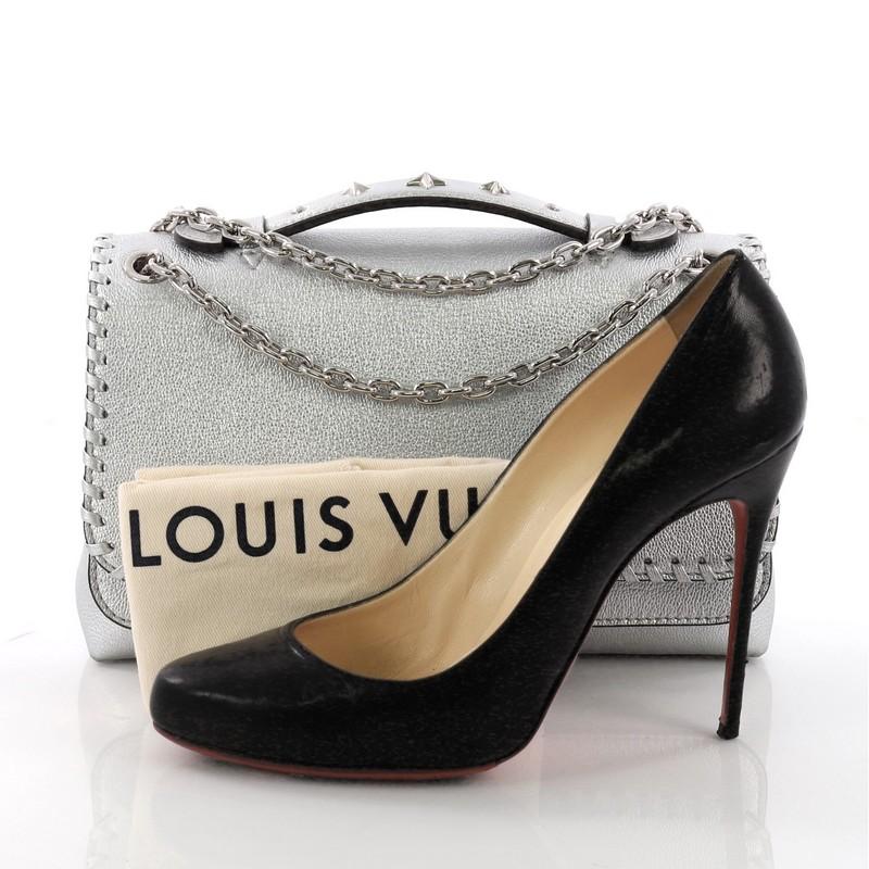 This Louis Vuitton Very Chain Bag Whipstitch Leather, crafted in silver leather, features single top leather handle with studs, chain link strap, and silver-tone hardware. Its flap opens to a silver microfiber interior divided into two compartments