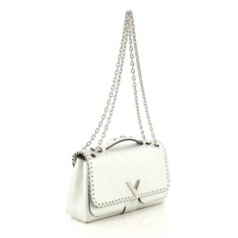 This Louis Vuitton Very Chain Bag Whipstitch Leather, crafted in metallic silver leather, features single top leather handle with studs, chain link strap, whipstitch detailing, and silver-tone hardware. Its flap opens to a gray microfiber interior