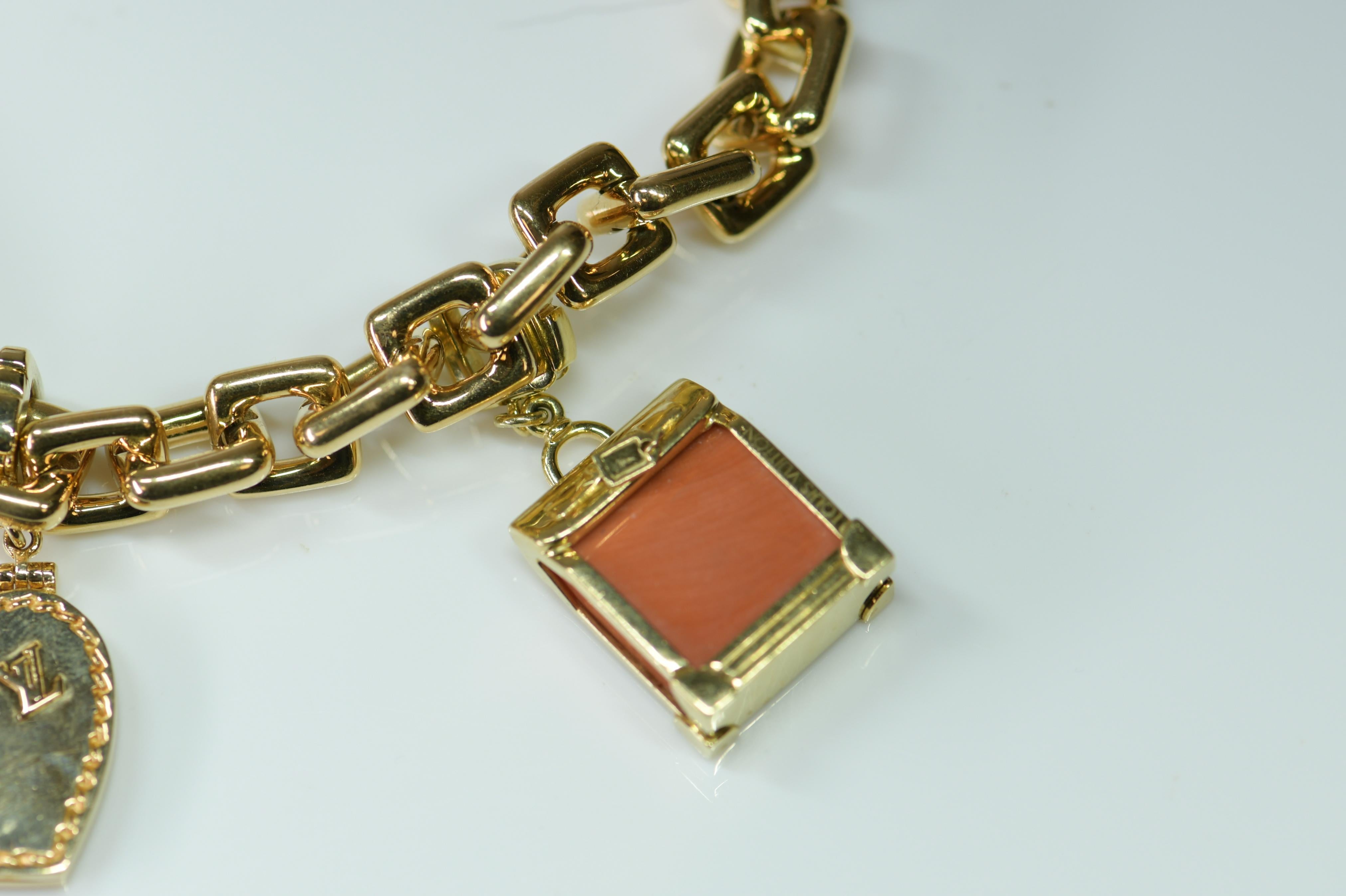 A wonderful authentic Louis Vuitton 18K yellow gold and charm bracelet, four assorted detachable and gem-set charms including a coral steamer, a gold heart shape locket, a gold padlock, and a pair of gold keys. Bracelet and each charm with maker's