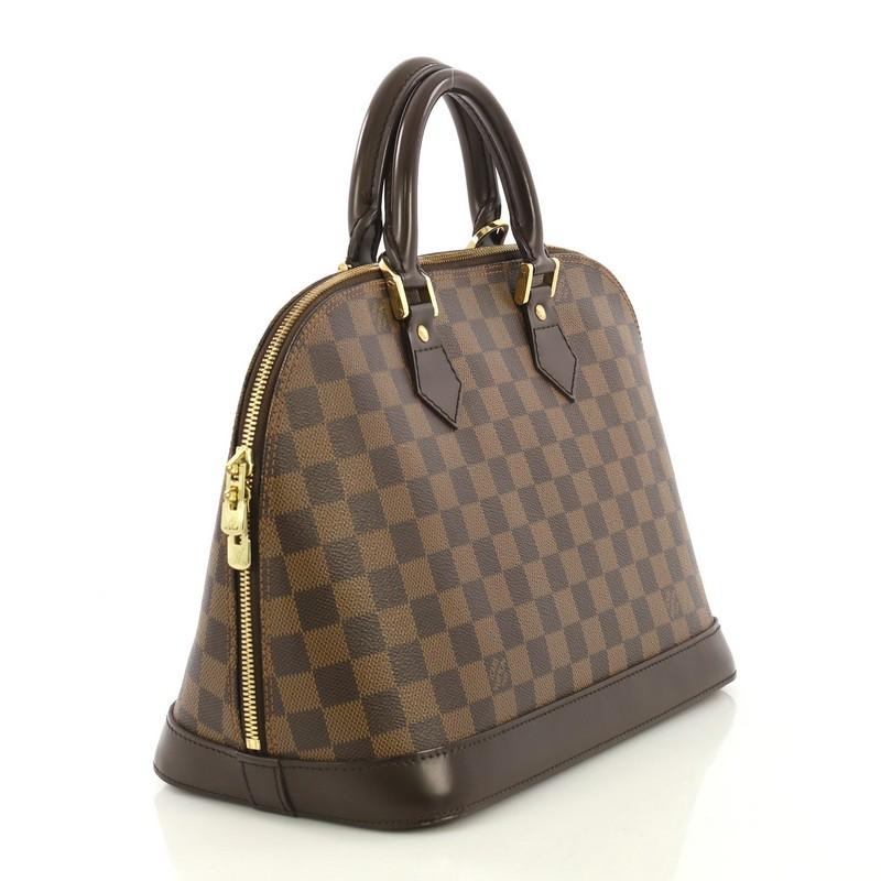 This Louis Vuitton Vintage Alma Handbag Damier PM, crafted from damier ebene coated canvas, features dual rolled handles, dark brown leather trim, and gold-tone hardware. Its two-way zip closure opens to an orange fabric interior with slip pockets.