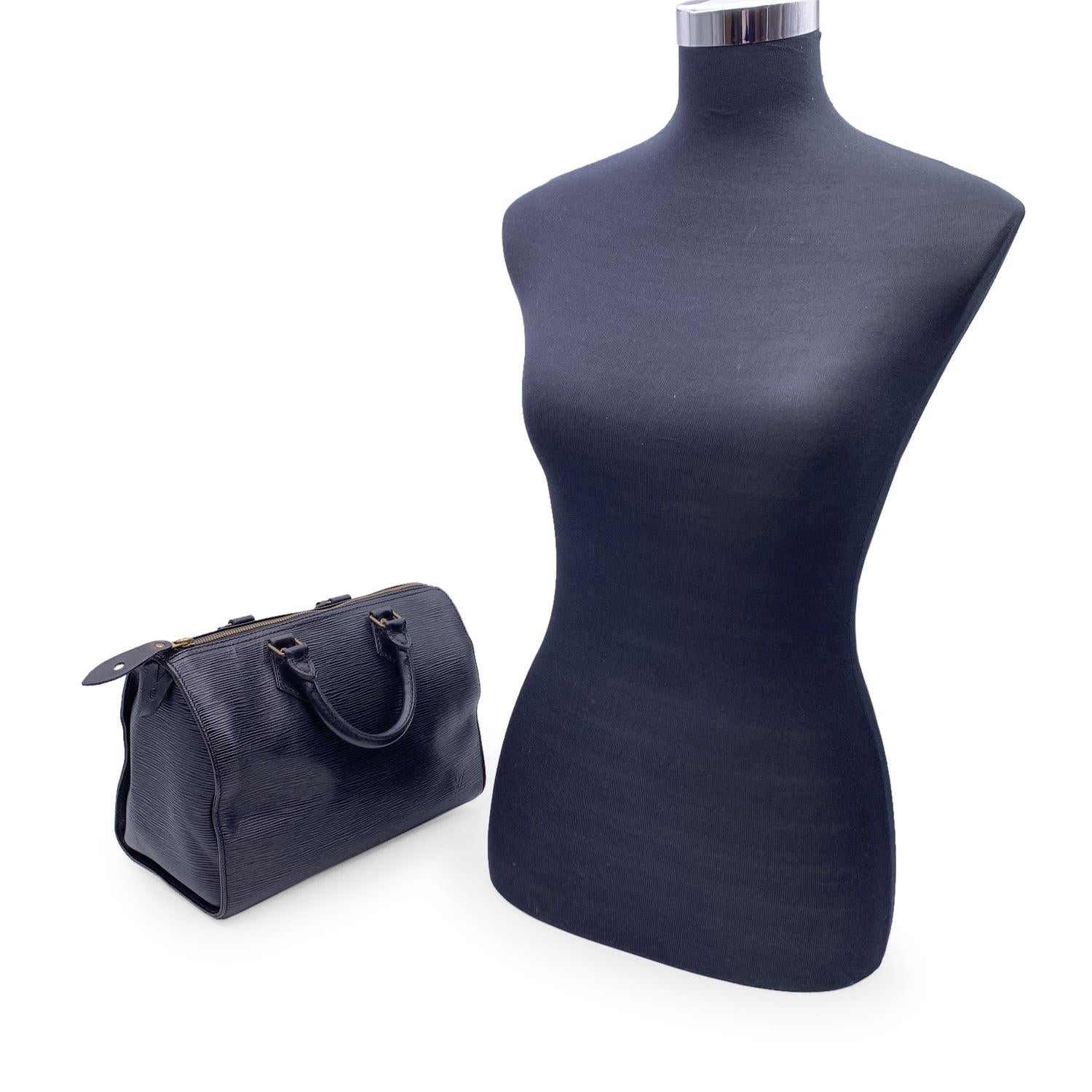 Ce classique Louis Vuitton Speedy 28, l'une des lignes les plus populaires, est en cuir épi noir. Forme arrondie, double poignée en cuir. Doublure en daim noir. Matériel en métal doré. Fermeture à glissière sur le dessus. 1 poche ouverte à