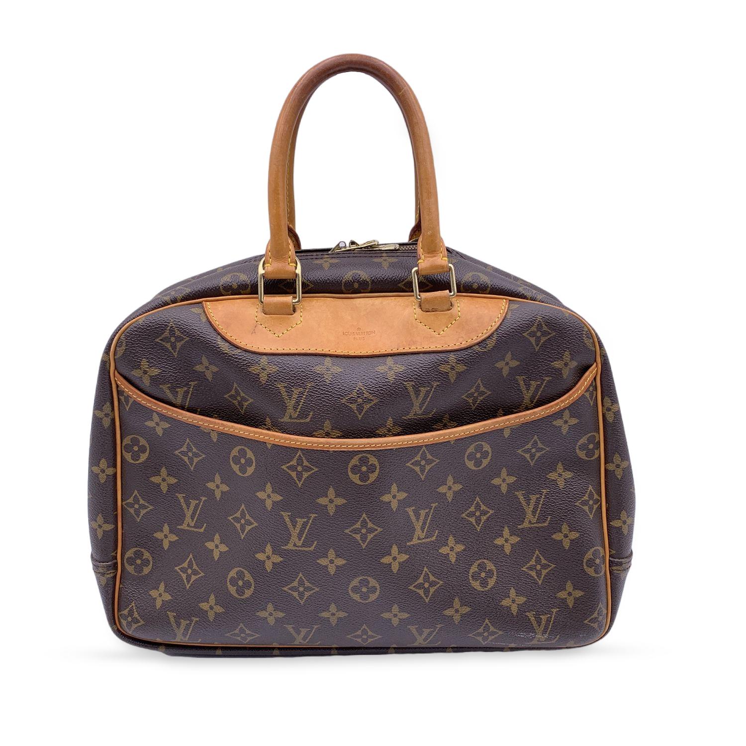 Louis Vuitton DEAUVILLE Sac conçu en toile Monogram intemporelle avec garniture et poignées en cuir véritable. Fermeture à glissière supérieure. 1 poche extérieure ouverte. Doublure beige lavable avec 4 poches ouvertes, 1 sangle élastique pour