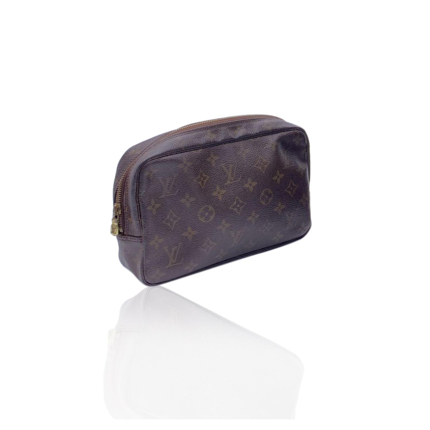 LOUIS VUITTON Monogram trousse Toiletry 23 cosmetic bag. Brown monogram coated canvas. Brass hardware. Upper zipper closure Beige lining. 1 side open pocket inside and elasticated straps to hold bottle and cosmetics. 'LOUIS VUITTON Paris - Made in