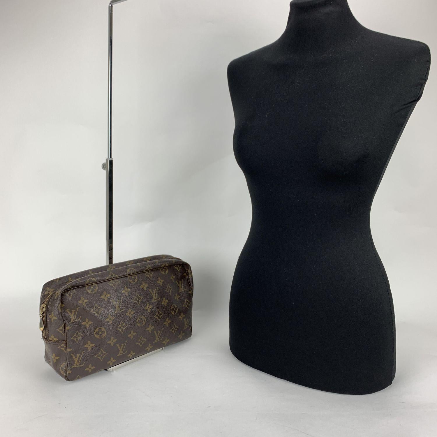 LOUIS VUITTON Monogram trousse Toiletry 28 cosmetic bag. Brown monogram coated canvas. Brass hardware. Upper zipper closure (Unfortunately the zip does not close completely). Beige lining. 1 side open pocket inside and elasticated straps to hold