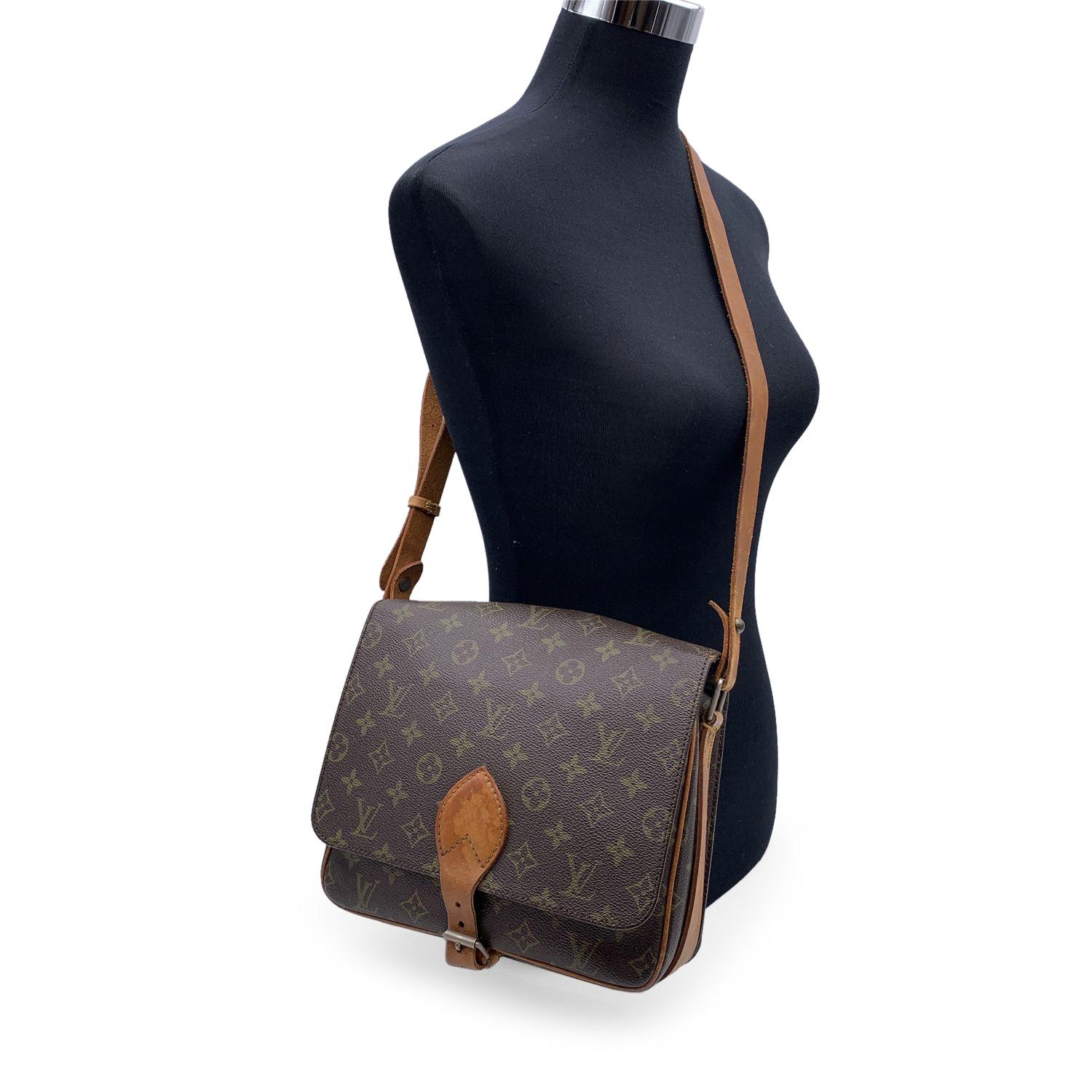 Louis Vuitton Vintage Monogram Canvas Cartouchiere MM Bag. Brown Monogram Canvas with genuine leather trim. It features a square shape with a flap top and buckle closure. Its interior in brown leather. Divider in the bag separating the inside into