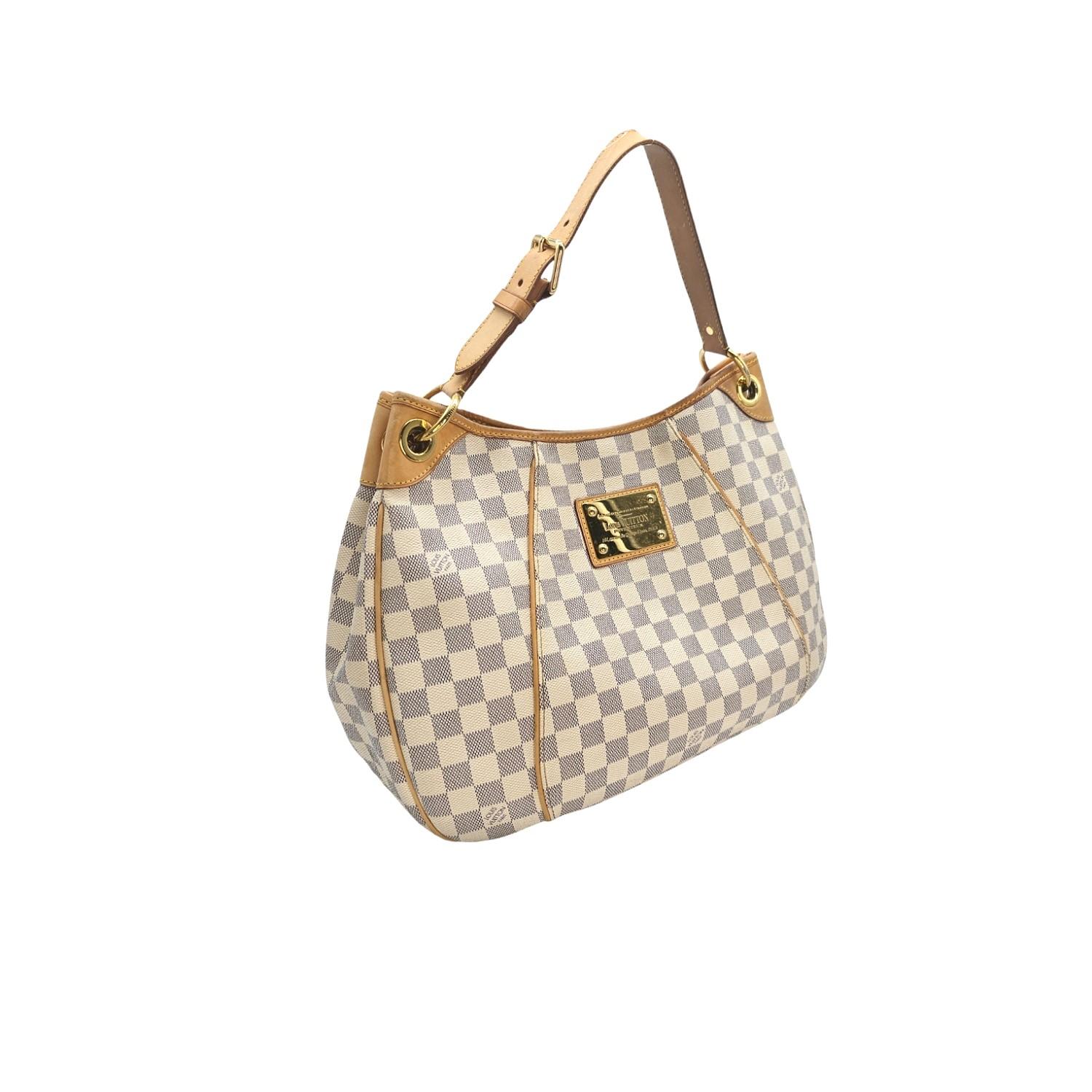 This Louis Vuitton Galleria GM was made in France and it is crafted of the Louis Vuitton Damier Azur coated canvas exterior with leather trimming and gold-tone hardware features. It features a magnetic snap closure that opens up to an Alcantara