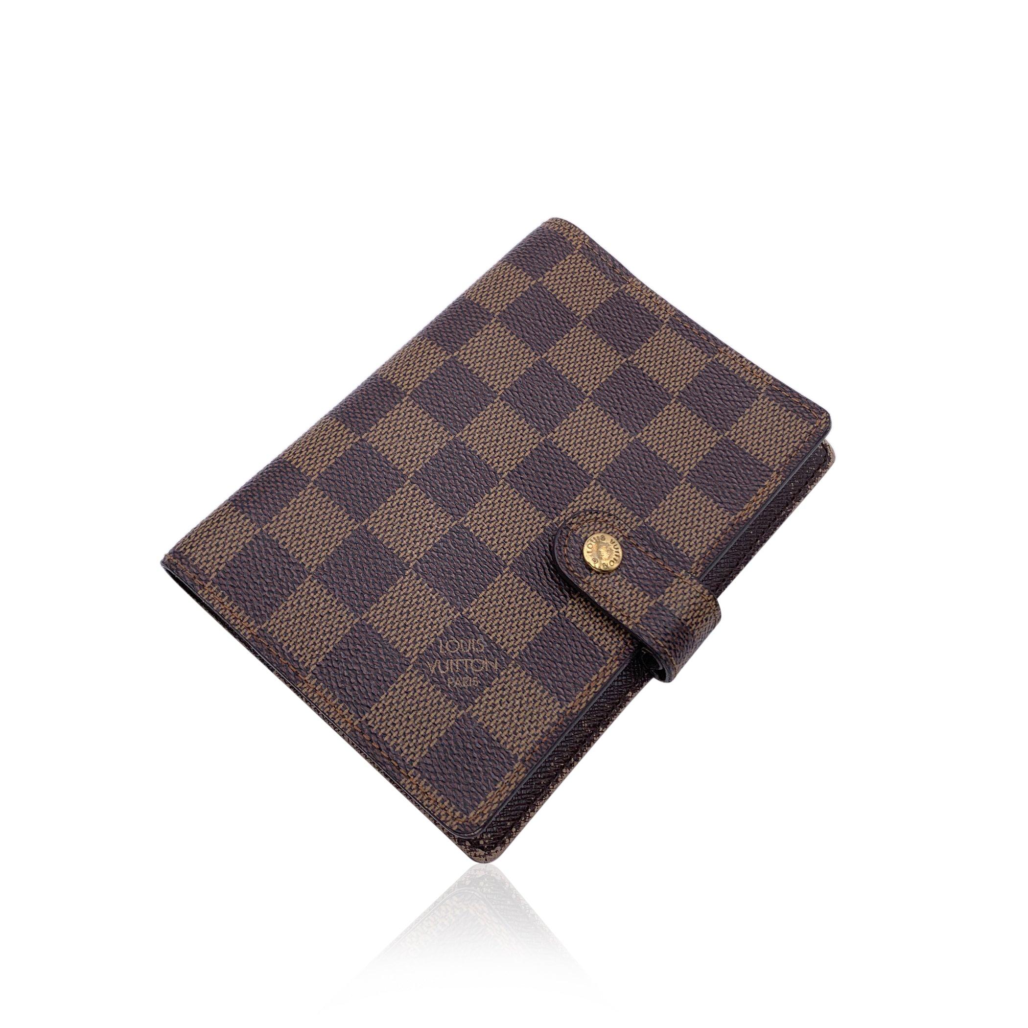 Agenda cover in brown Damier canvas by LOUIS VUITTON. Press stud closure. Brown leather interior. Six- Ring binder. 1 pen holder. 3 credit card slots. 2 side sleeve for papers. Authenticity serial number embossed inside. 'Louis Vuitton - made in