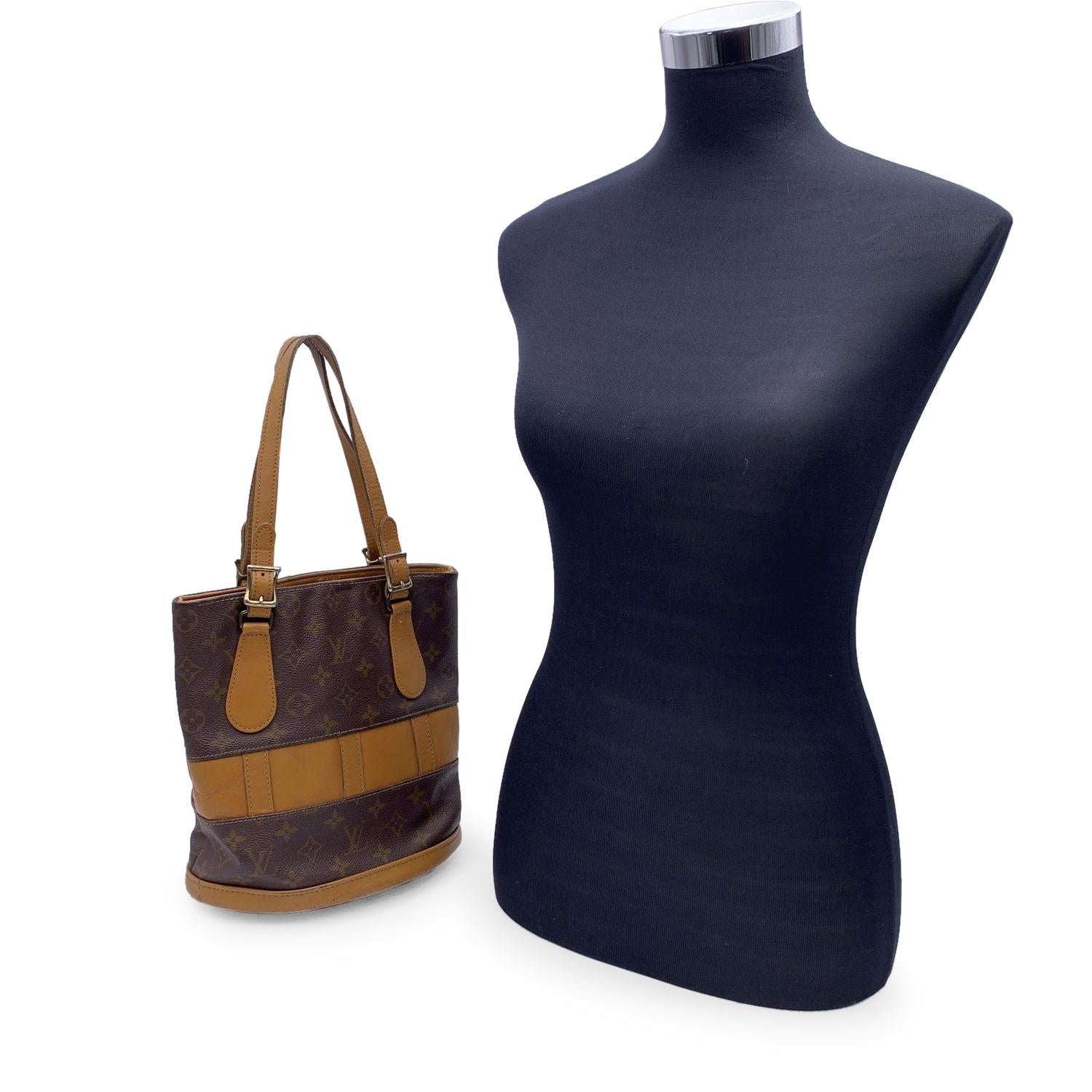 Vintage LOUIS VUITTON Monogram small Bucket Bag, crafted in monogram canvas with caramel colored cowhide leather trim and handles. The interior of the bag is a brown fabric with a zip pocket and a chain with a removable pouch. Louis Vuitton French