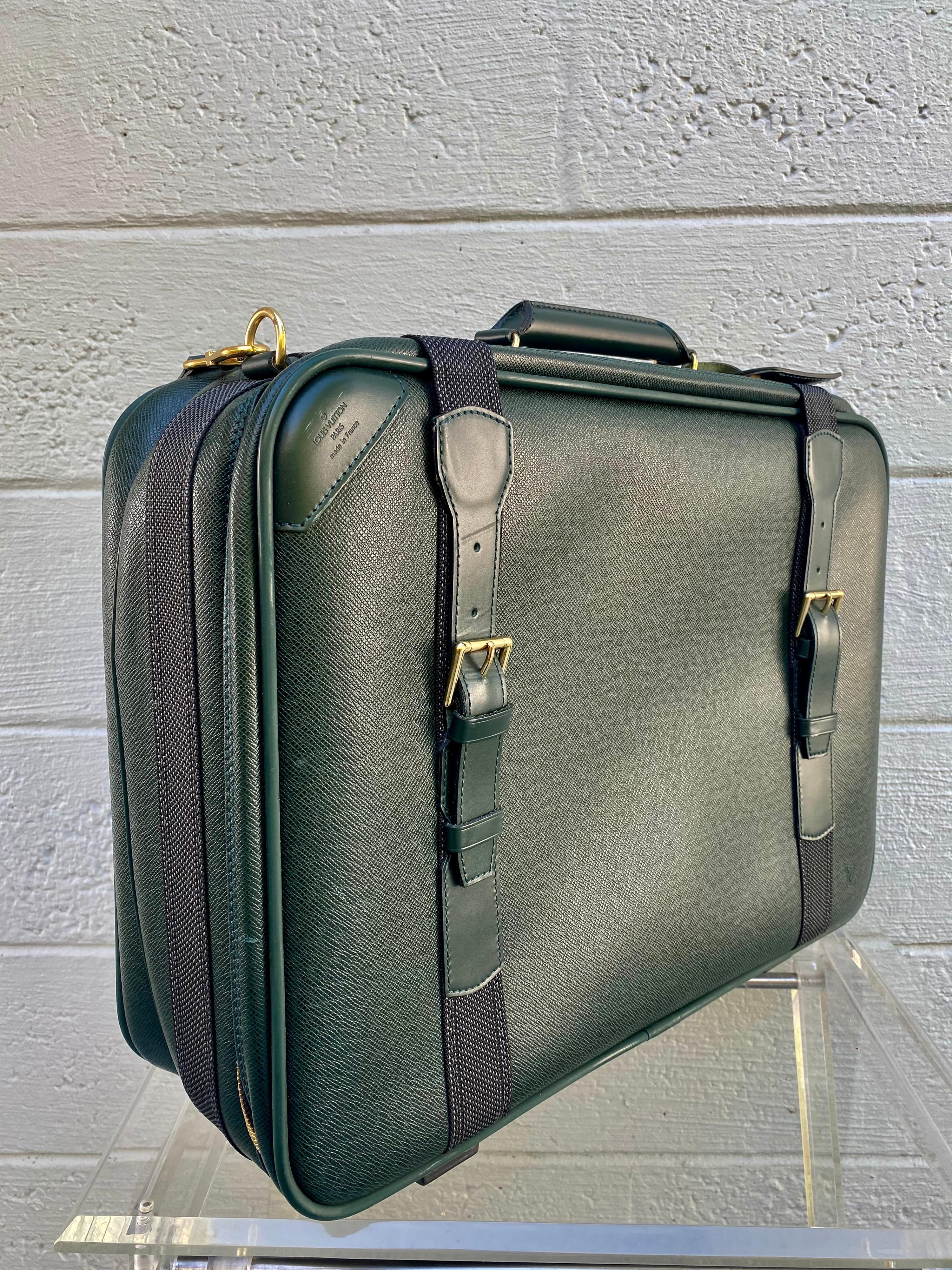The vintage Louis Vuitton Satellite Taiga Leather carry on is crafted from hunter green leather, features a single rolled leather handle, cowhide leather trim, buckle straps and aged gold-tone hardware. Its two-way zip closure opens to a gray