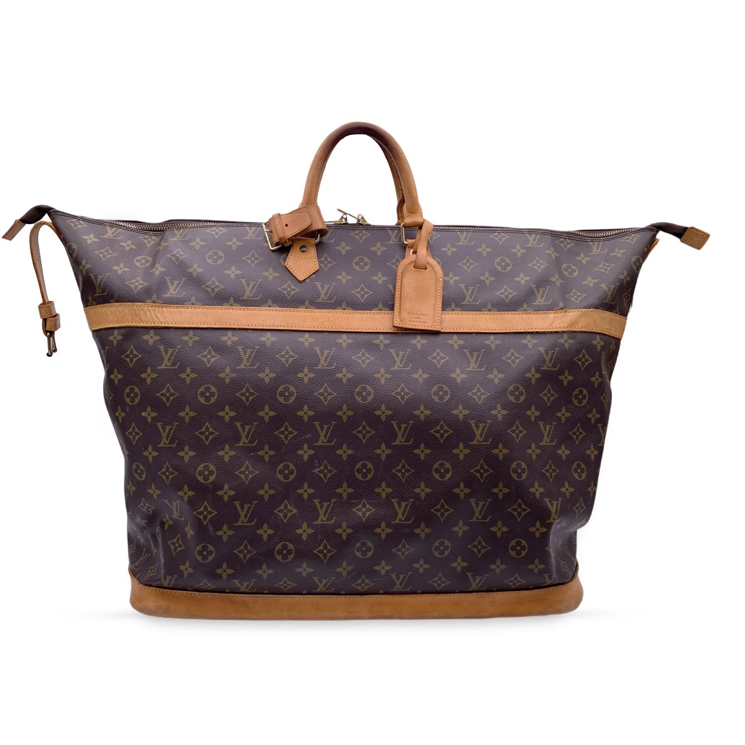 Louis Vuitton 'Cuiser 50' Travel bag. Monogram canvas and beige leather trim. Double zip closure with original padlock and key included and additional strap with buckle closure on the top. Brown canvas lining.1 open pocket inside. Gold metal pieces.