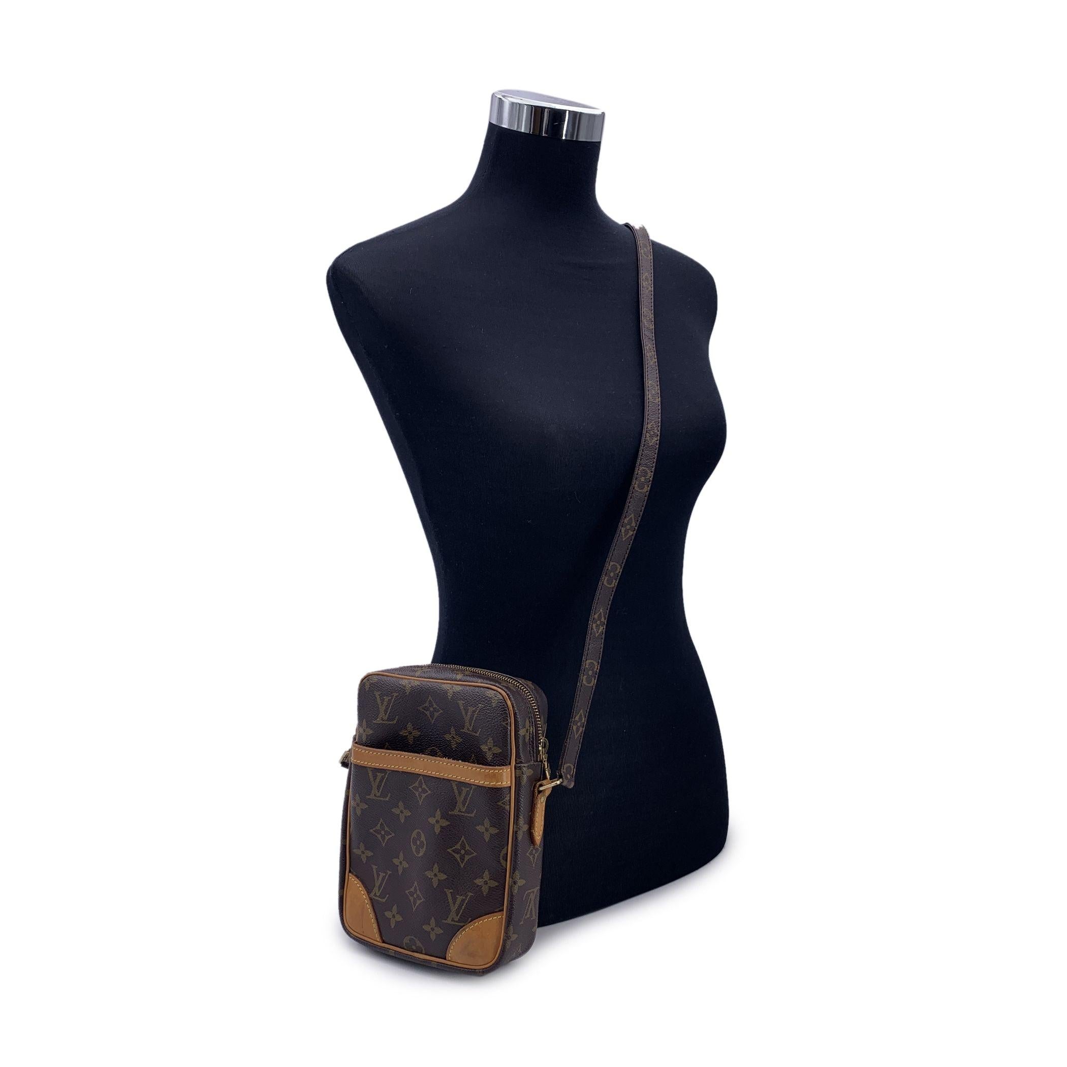 Stylish DANUBE messenger bag by LOUIS VUITTON, crafted in timeless monogram canvas. The bag features tan leather trim, a front open pocket and gold metal hardware. Adjustable monogram canvas shoulder strap with shoulder pad. The top zipper opens to