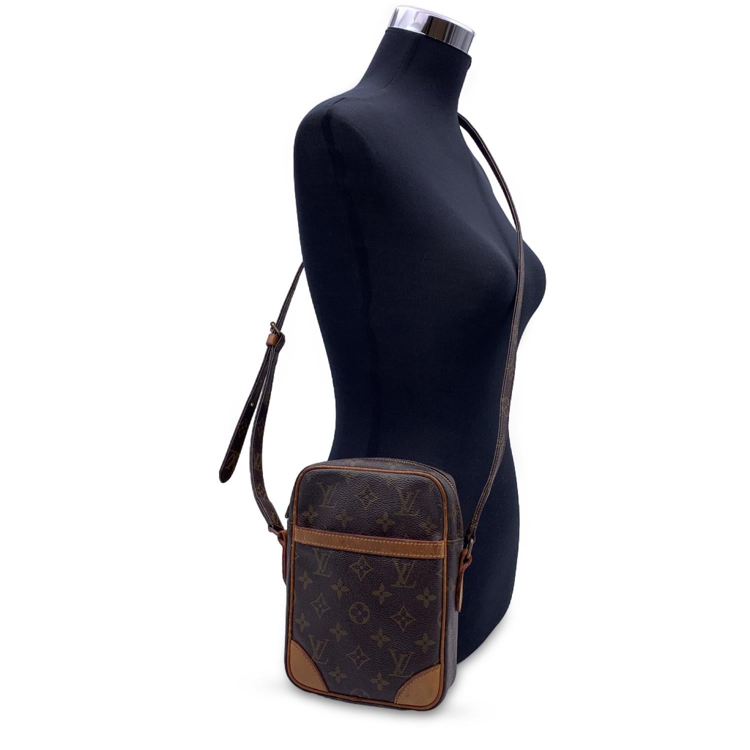Stylish DANUBE messenger bag by LOUIS VUITTON, crafted in timeless monogram canvas. The bag features tan leather trim, a front open pocket and gold metal hardware. Adjustable monogram canvas shoulder strap with shoulder pad. The top zipper opens to