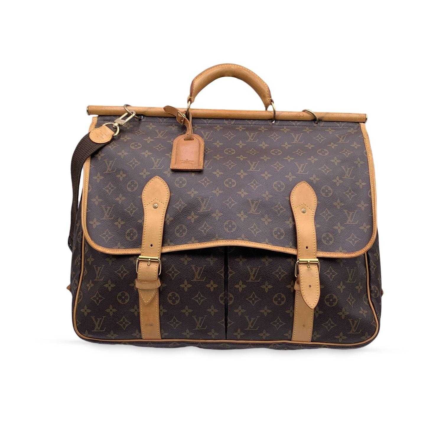 Louis Vuitton Chasse Garment Bag in Monogram canvas. 2 internal compartments, one on each side. It features rounded handles and a removable and adjustable shoulder strap in fabric. Zip and buckle closure. Original Louis Vuitton padlock attached to