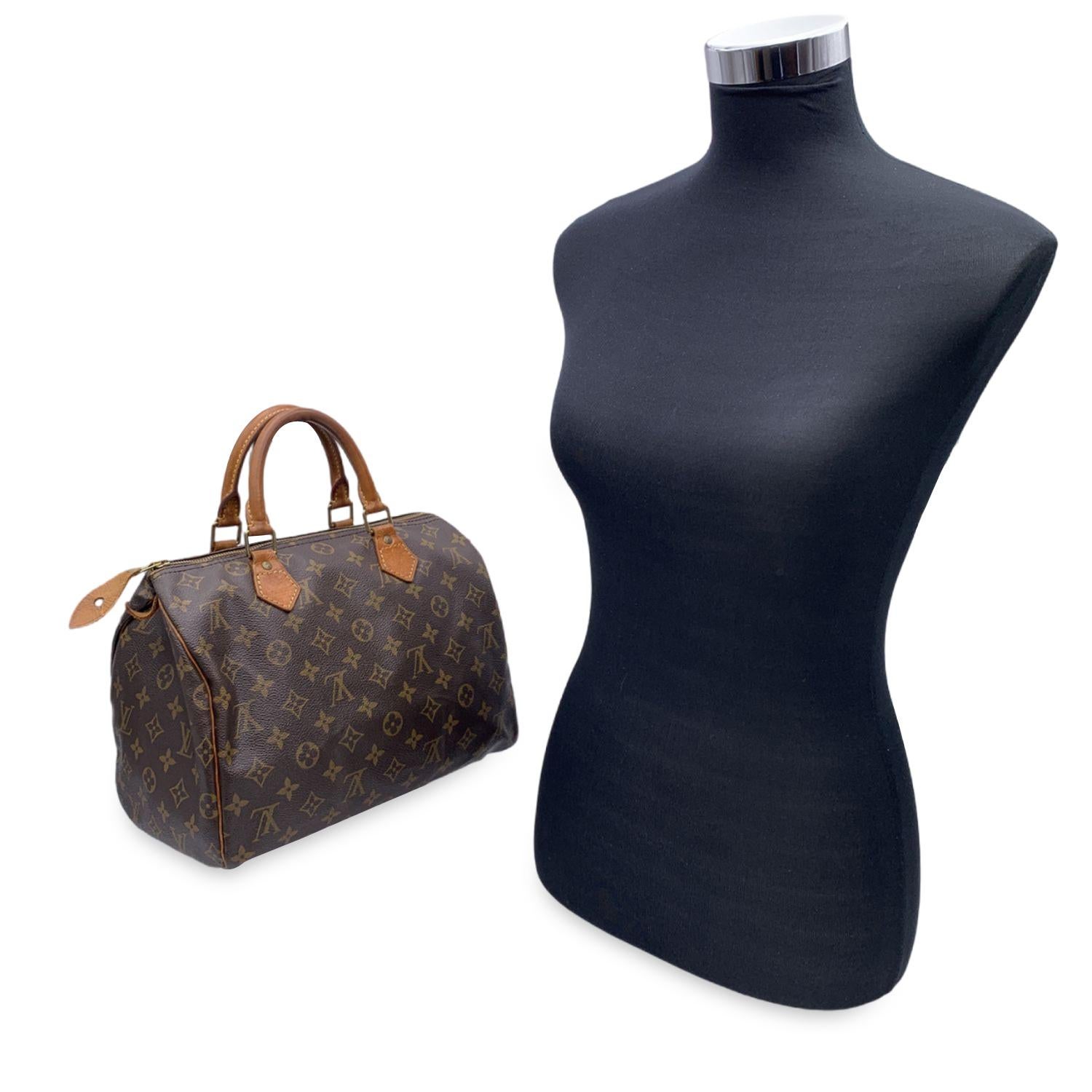 This classic Louis Vuitton SPEEDY 30, one of the most popular lines in the LV monogram. Rounded shape with double leather handles. Brown monogram canvas. Gold metal hardware. Upper zipper closure. Brown canvas lining. 1 open pocket inside. 'LOUIS