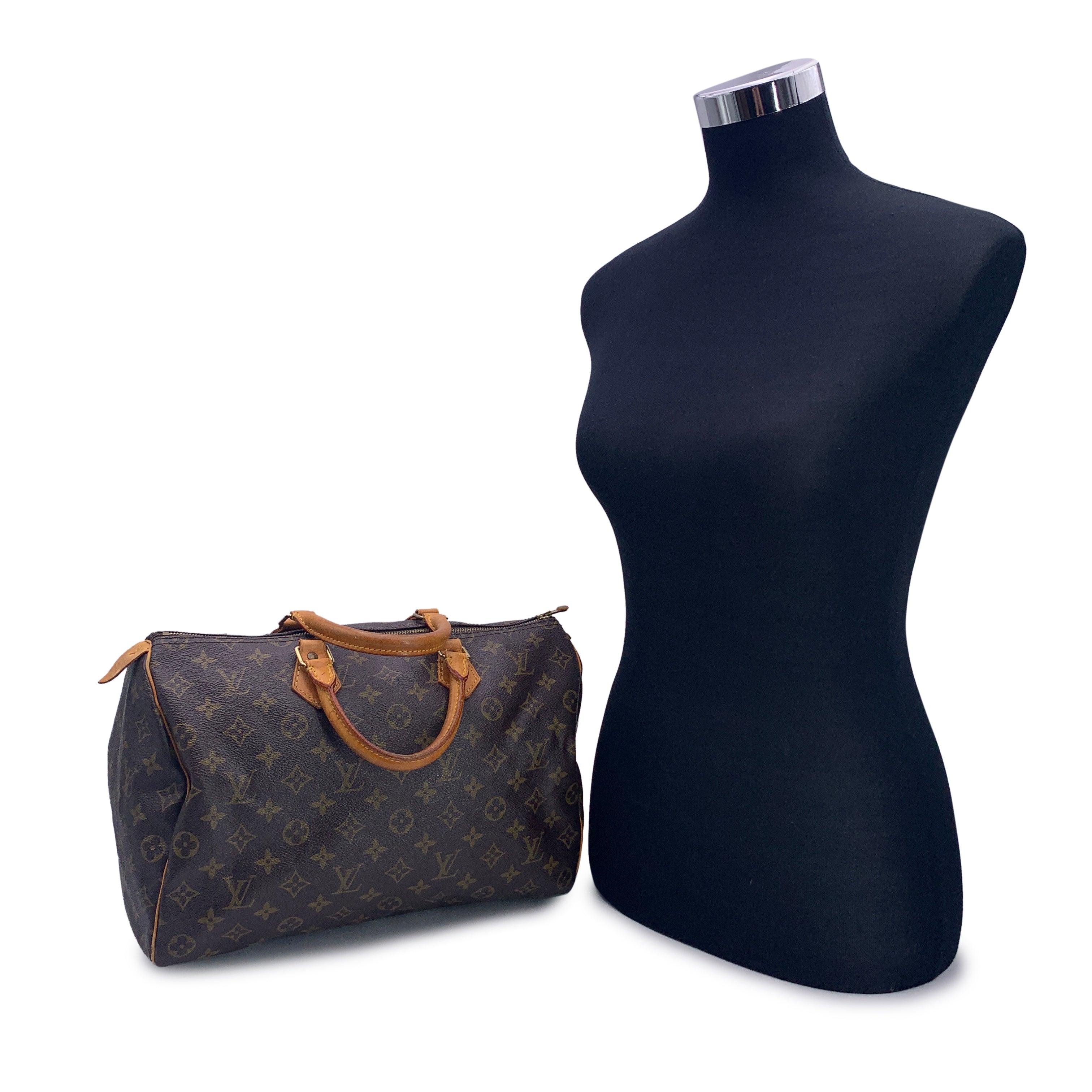 Ce classique Louis Vuitton SPEEDY 35, l'une des lignes les plus populaires du monogramme LV. Forme arrondie, double poignée en cuir et passepoil. Toile monogramme marron. Ferrures en métal doré signées. Fermeture à glissière sur le dessus avec