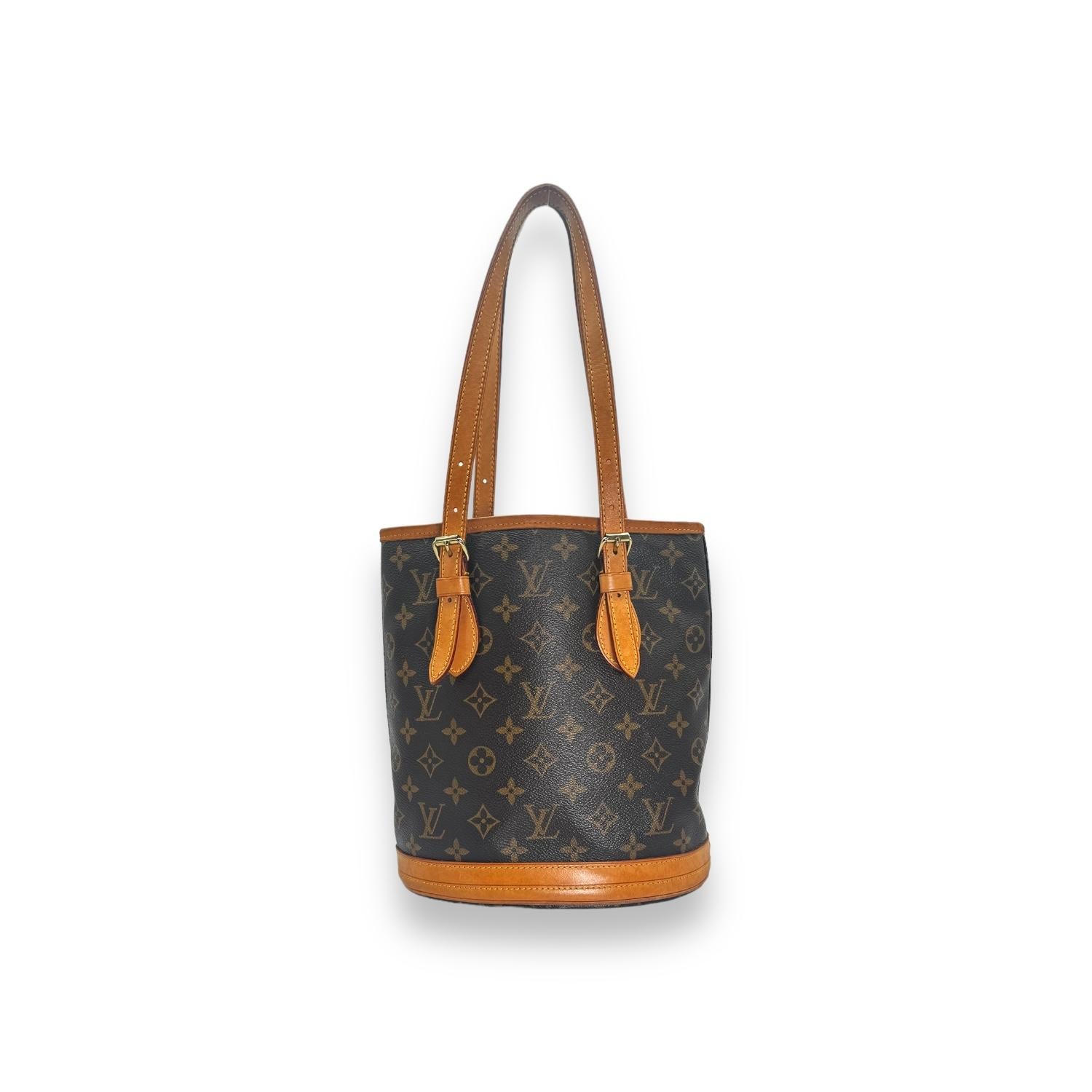 This Louis Vuitton Vintage Monogram Petit Bucket Bag is made from the iconic LV Monogram Canvas and Cowhide Leather Trim, this November 2004 piece exudes elegance and charm. It features a leather-lined interior with dual pockets and brass hardware,