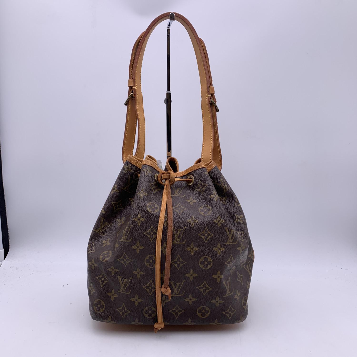 Iconic ' Petit Noé' bucket bag by LOUIS VUITTON was first created in 1932 to carry champagne bottles. Monogram canvas with genuine leather trim and shoulder strap. It features drawstring closure and brown canvas lining. Adjustable shoulder strap.
