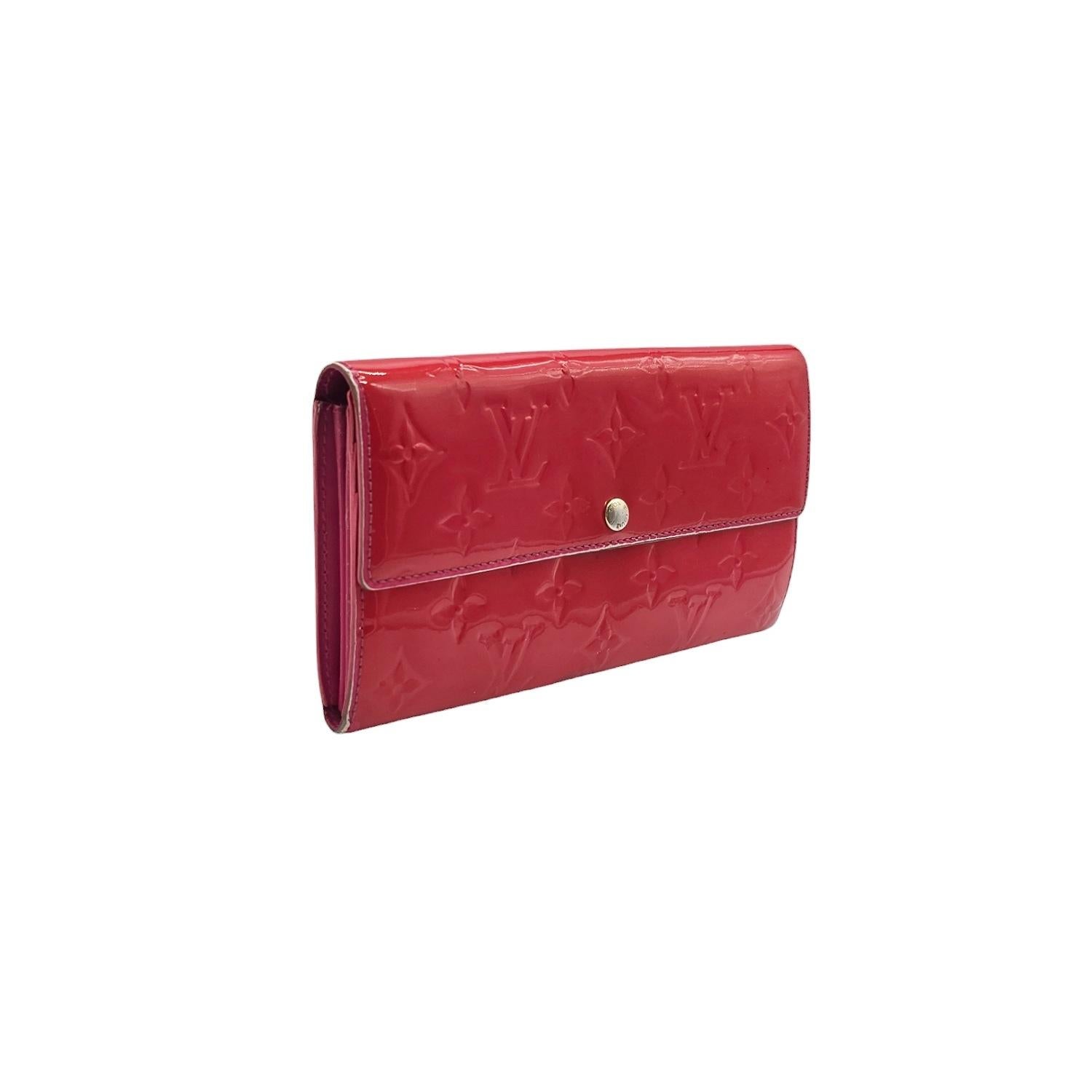 Indulge in luxury with the Louis Vuitton Monogram Sarah Vernis Wallet. Crafted in France in 2009, this wallet boasts a Monogram Vernis Patent Leather exterior with gold-tone hardware. The fold over snap closure opens up to a leather interior with