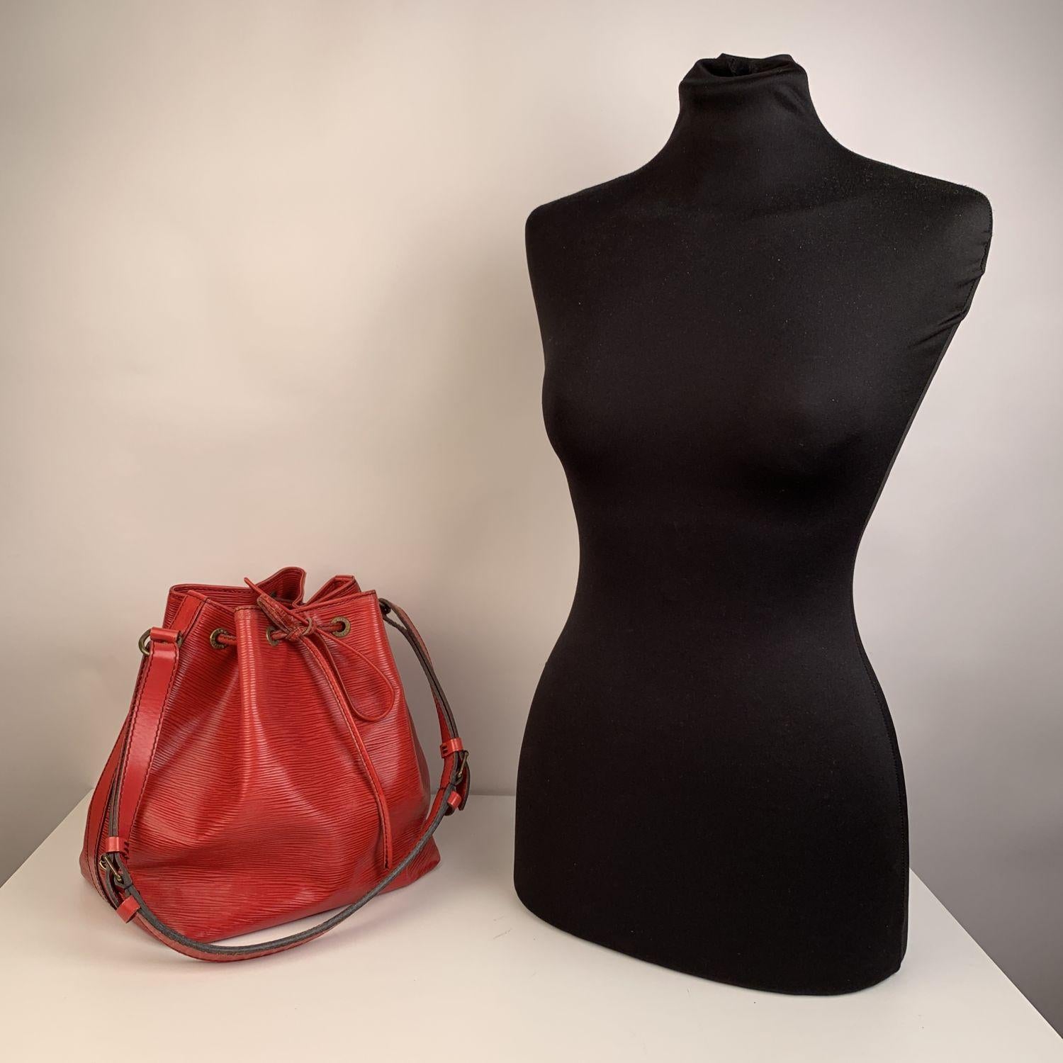 Iconic ' Petit Noé' bucket bag by LOUIS VUITTON was first created in 1932 to carry champagne bottles. Red Epi leather with drawstring closure and microfibrer lining. 1side zip pocket. Adjustable shoulder strap

Logos / Tags: LV - LOUIS VUITTON logo