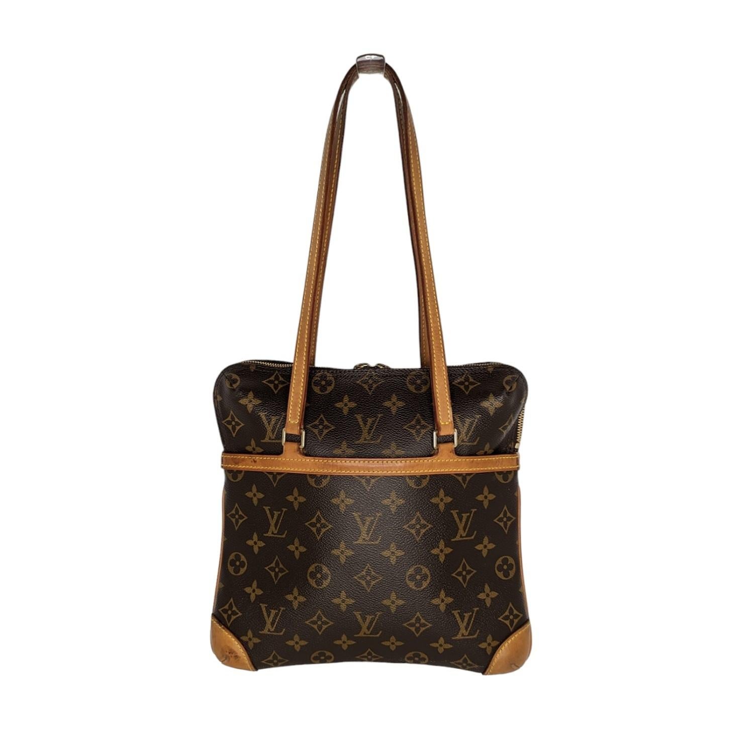This lovely shoulder bag is crafted of classic Louis Vuitton monogram toile canvas with vachetta cowhide leather trim and strap handles. The bag features a front patch pocket and the brass top zipper opens to a red microfiber interior with patch