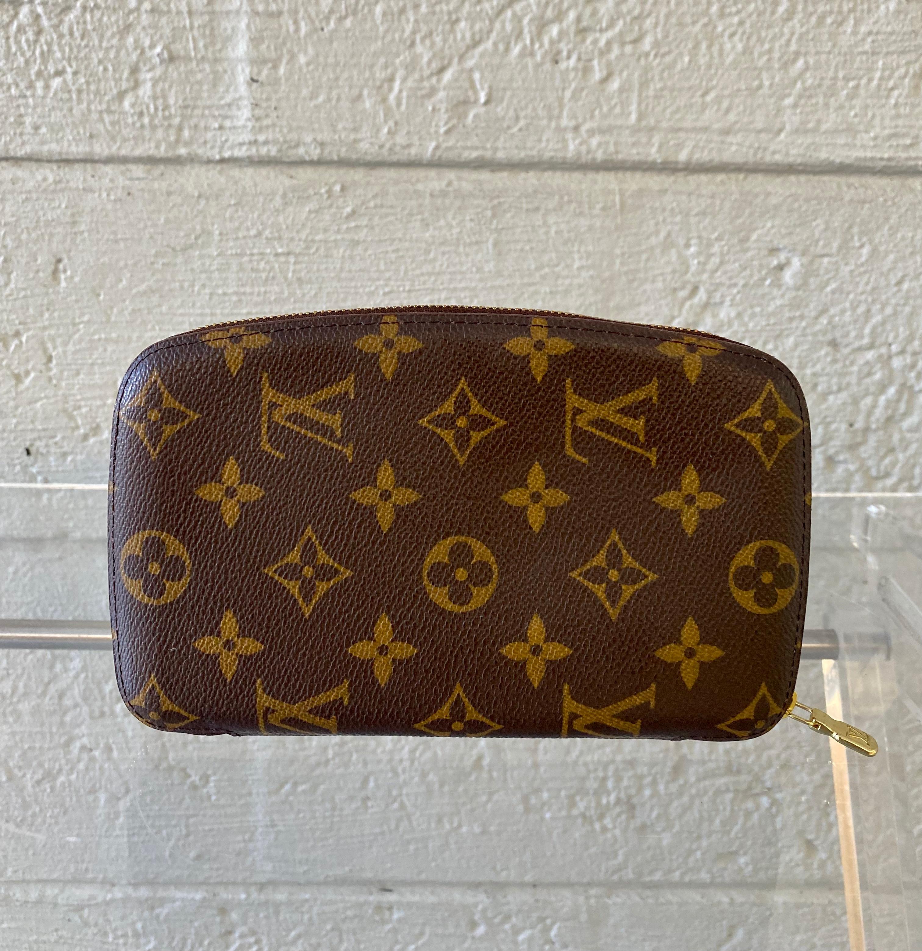 This vintage wallet is crafted of signature Louis Vuitton monogram on toile canvas. This wallet features a brass wrap-around zipper that opens to a cross-grain leather interior with card slots and three patch pockets. It holds you iPhone as well.