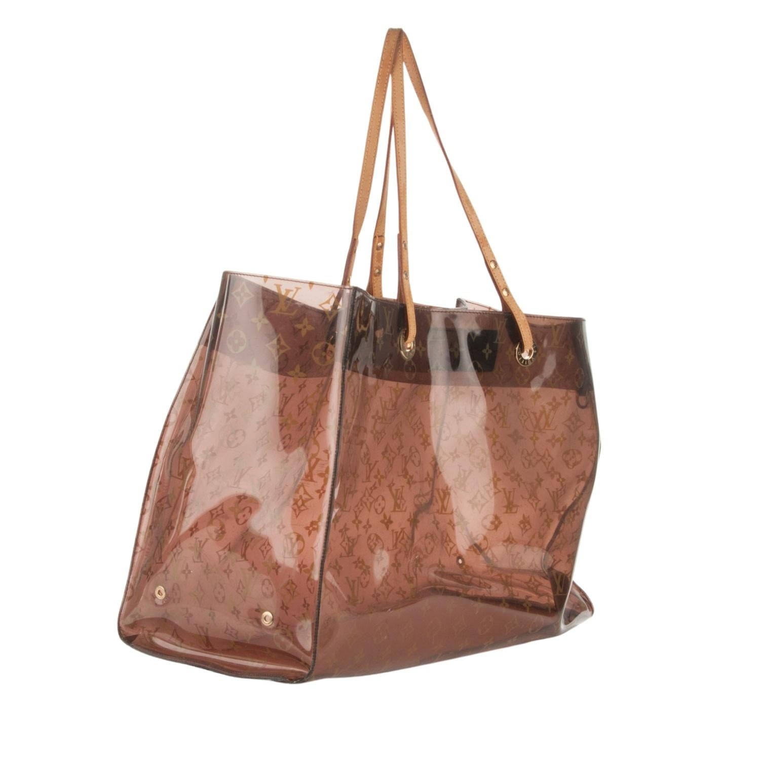 This Louis tote bag is made of a transparent vinyl with an amber tone and monogram print throughout. The bag features vachetta cowhide leather top handles, polished brass hardware and protective feet for the bottom. The top is open to a spacious