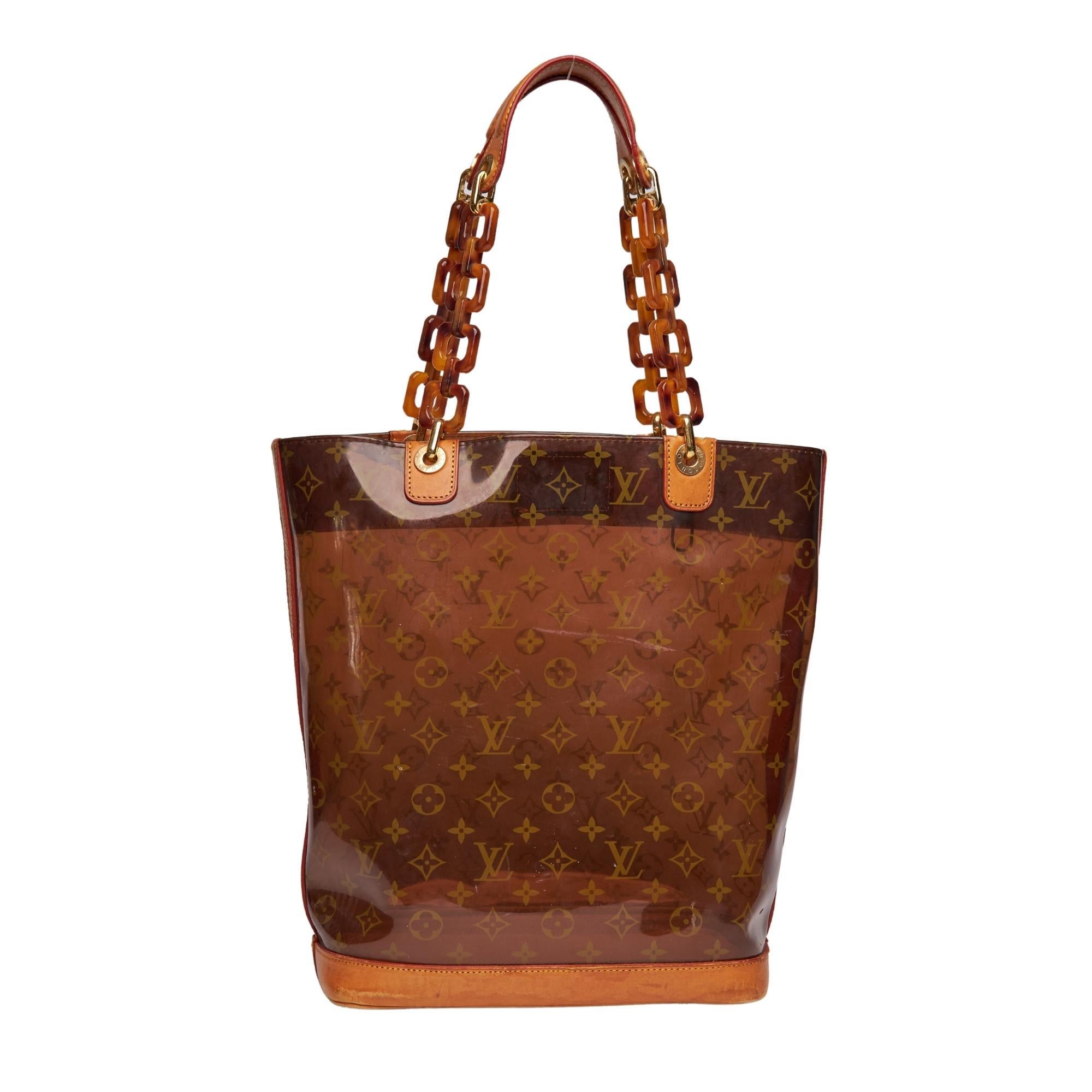 
This bag is made of vinyl with natural leather finishes. The bag features a transparent design with monogram print, dual leather and tortoiseshell-effect chain-link top handles, an attachable shoulder strap, an open top, a large main compartment, a