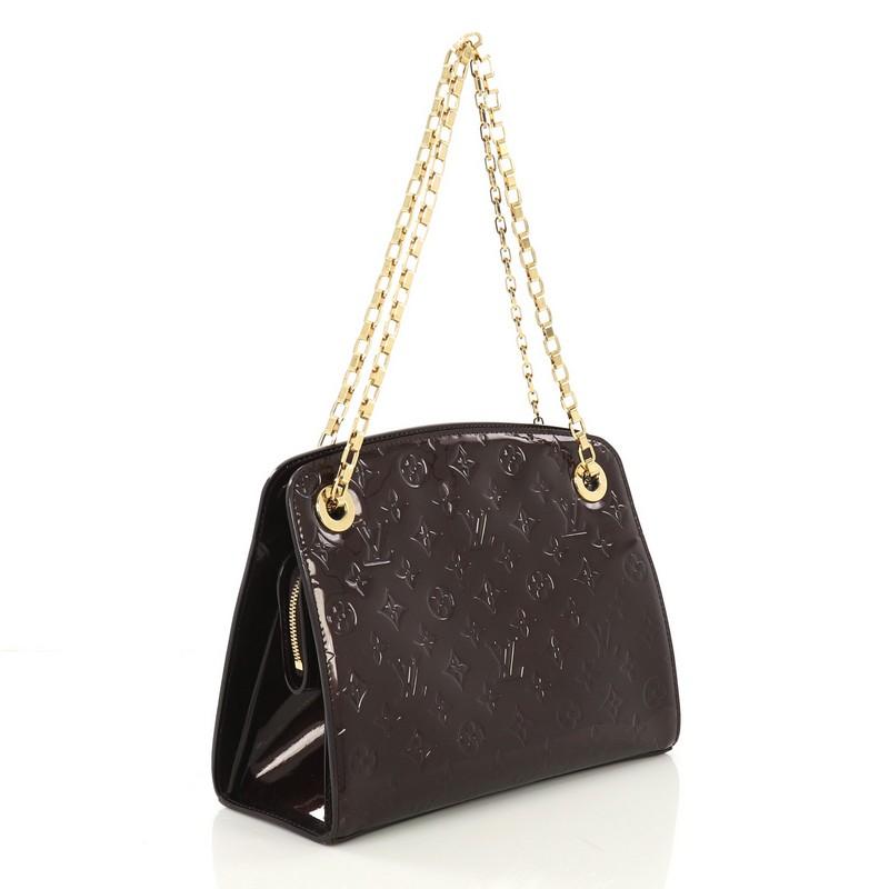 This Louis Vuitton Virginia Handbag Monogram Vernis MM, crafted from dark purple monogram vernis leather, features chain link strap, protective base studs and gold-tone hardware. Its clasped hook closure opens to a dark purple fabric interior with a