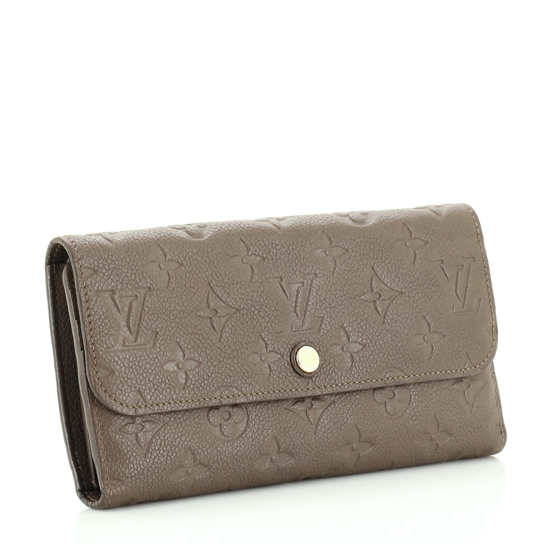 This Louis Vuitton Virtuose Wallet Monogram Empreinte Leather, crafted from neutral monogram empreinte leather, features gold-tone hardware. Its snap button closure opens to a neutral leather interior with multiple card slots, slip pocket and zip