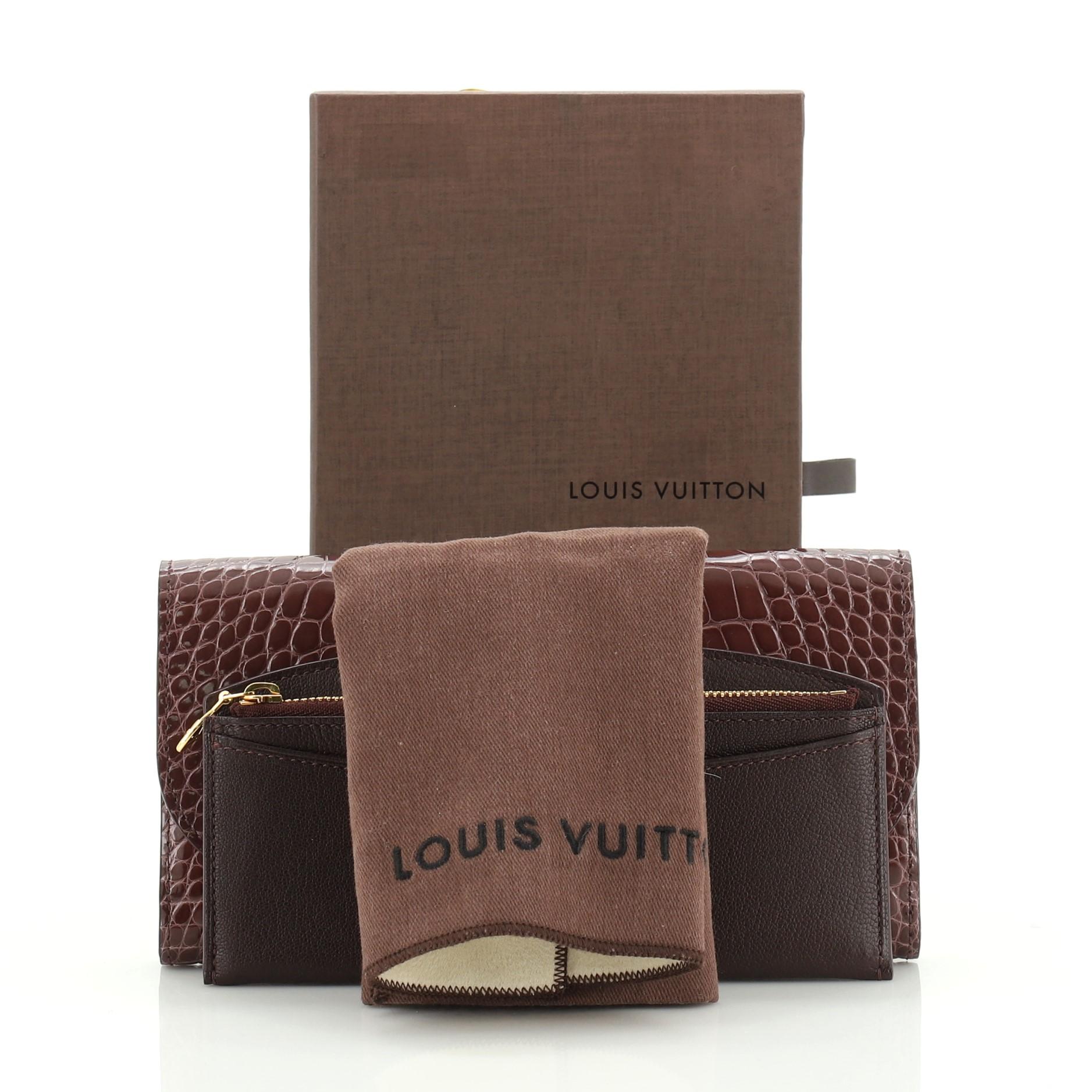 This Louis Vuitton Vivienne LV Wallet Alligator Long, crafted from genuine purple alligator, features an oversized LV logo snap closure and gold-tone hardware. Its flap opens to a brown leather interior with multiple card slots, slip pocket and zip