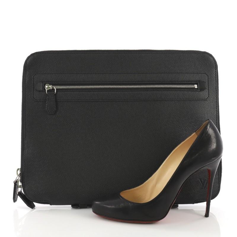 This Louis Vuitton Vladimir Portfolio Bag Taiga Leather, crafted in black taiga leather, features an exterior zip pocket, subtle LV logo, and silver-tone hardware. Its zip closure opens to a black leather interior with multiple pockets. Authenticity