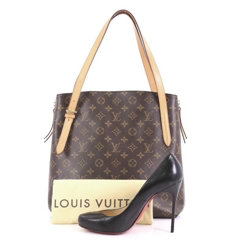This Louis Vuitton Voltaire Handbag Monogram Canvas, crafted in brown monogram coated canvas, features dual vachetta leather straps, protective base studs, side expandable zippers, and gold-tone hardware. Its clasp closure opens to a purple