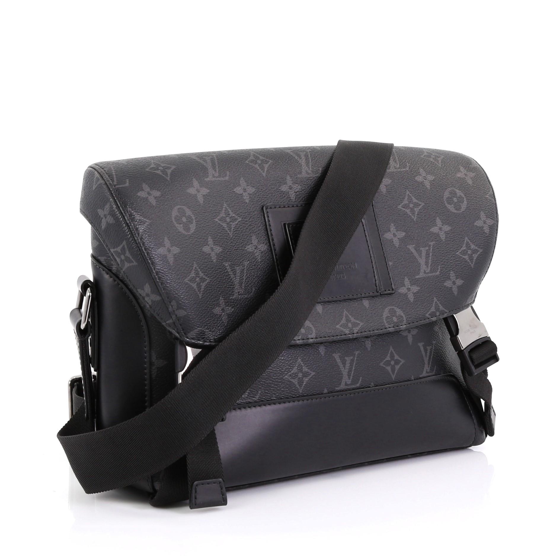 This Louis Vuitton Voyager Messenger Bag Monogram Eclipse Canvas PM, crafted from black monogram eclipse coated canvas, features an adjustable strap and silver-tone hardware. Its flap with buckle closures open to a black fabric interior with zip